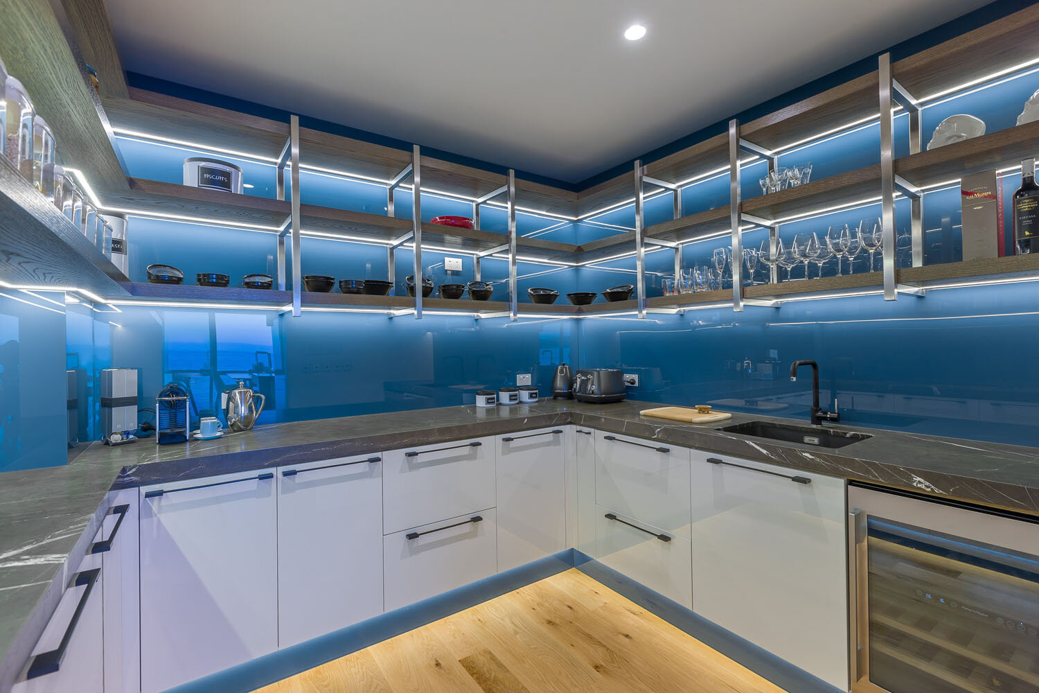 Scullery with blue feature glass splashback and glass between shelves