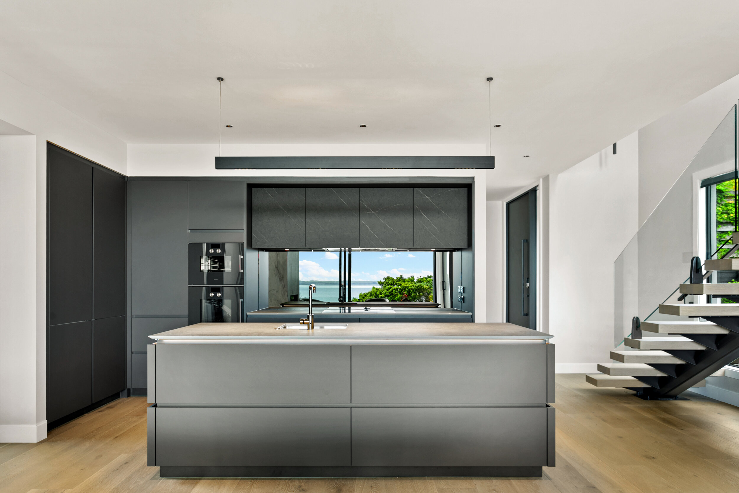 Smokey mirror glass splashback in modern two tone grey kitchen