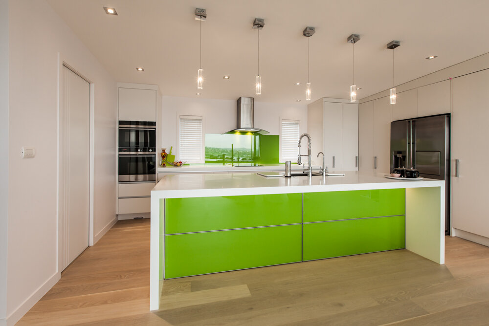 Green glass island panels in modern white kitchen