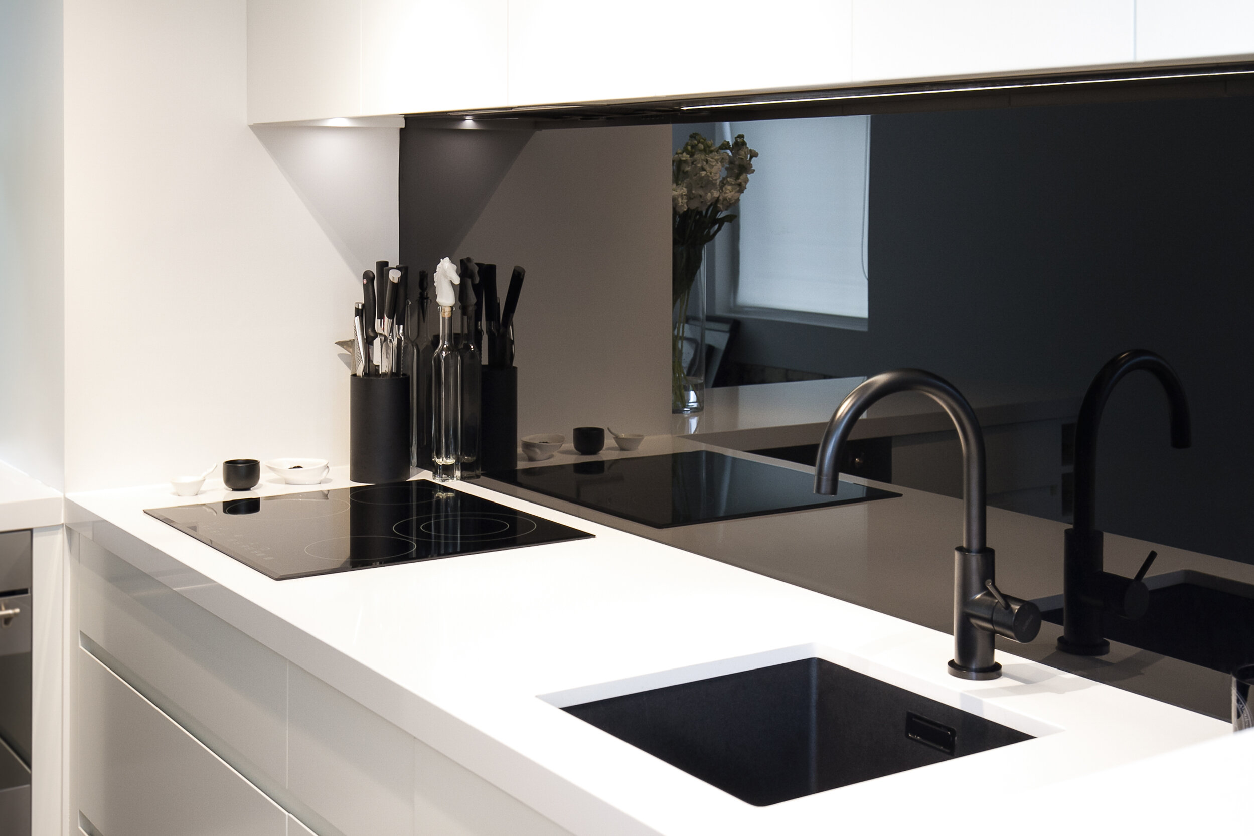 Black backpainted glass splashback in a modern white kitchen