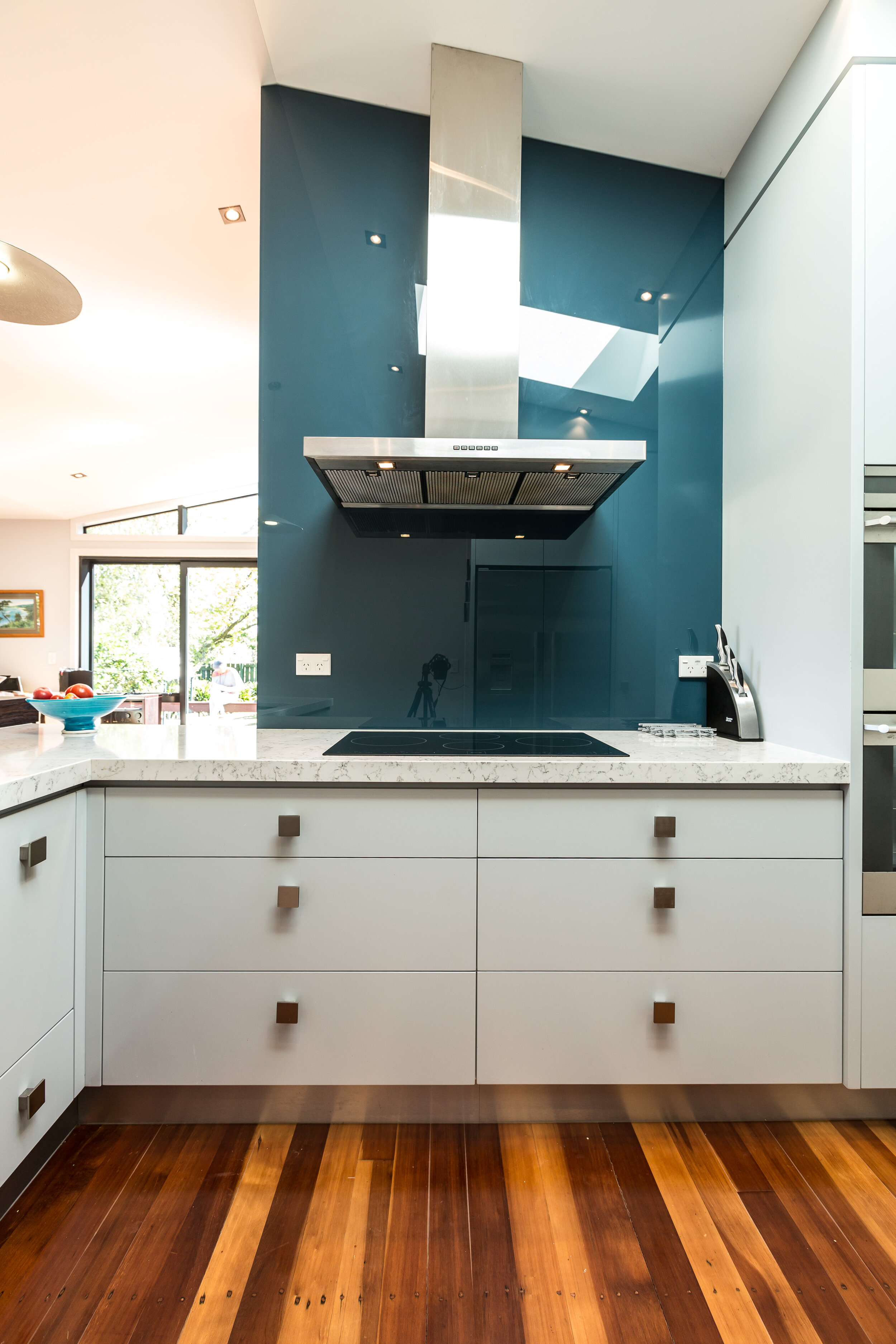 Full height angled glass splashback in teal blue in white kitchen