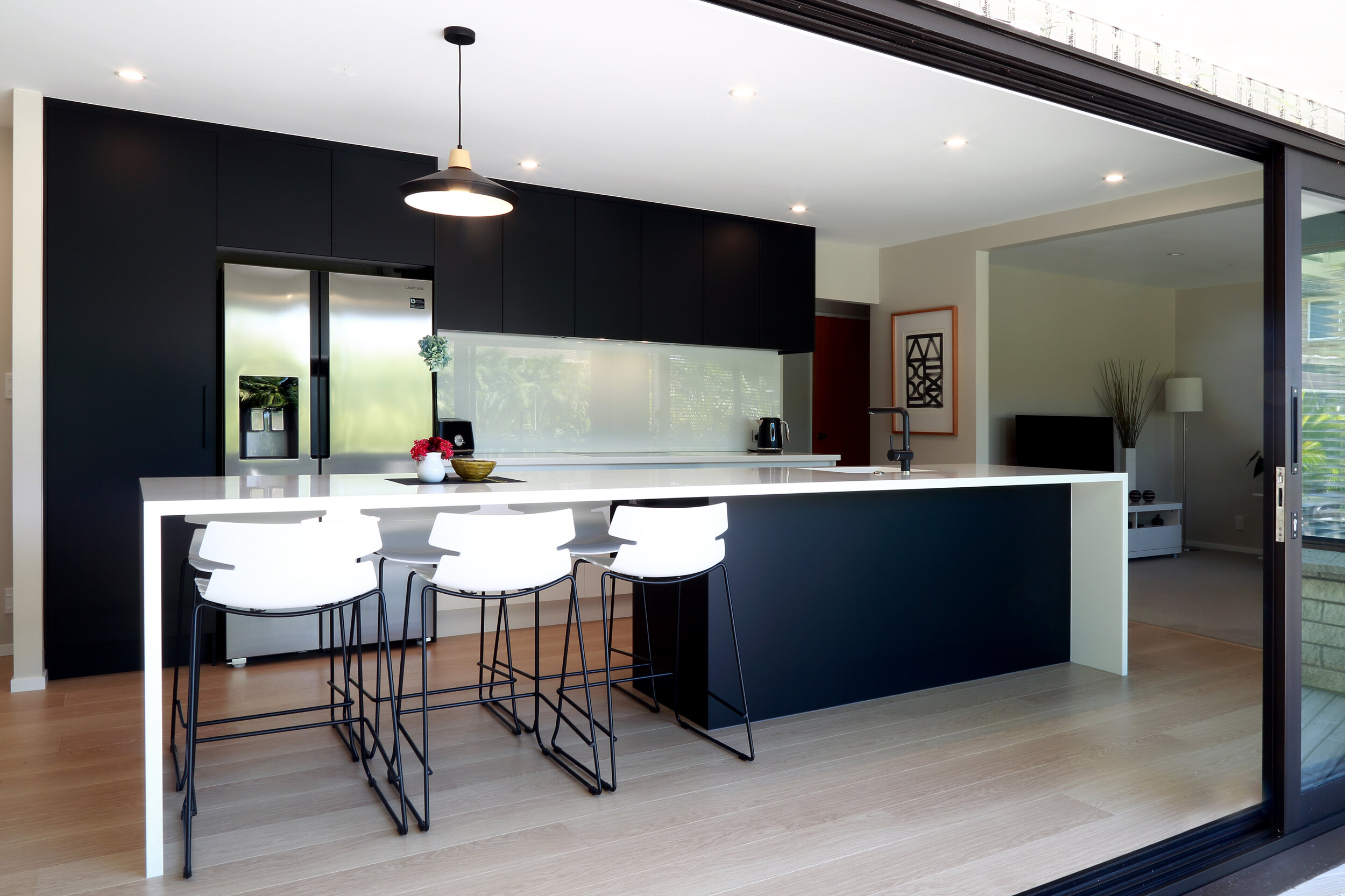 Galley kitchen with dark cabinetry and white backpainted glass splashback