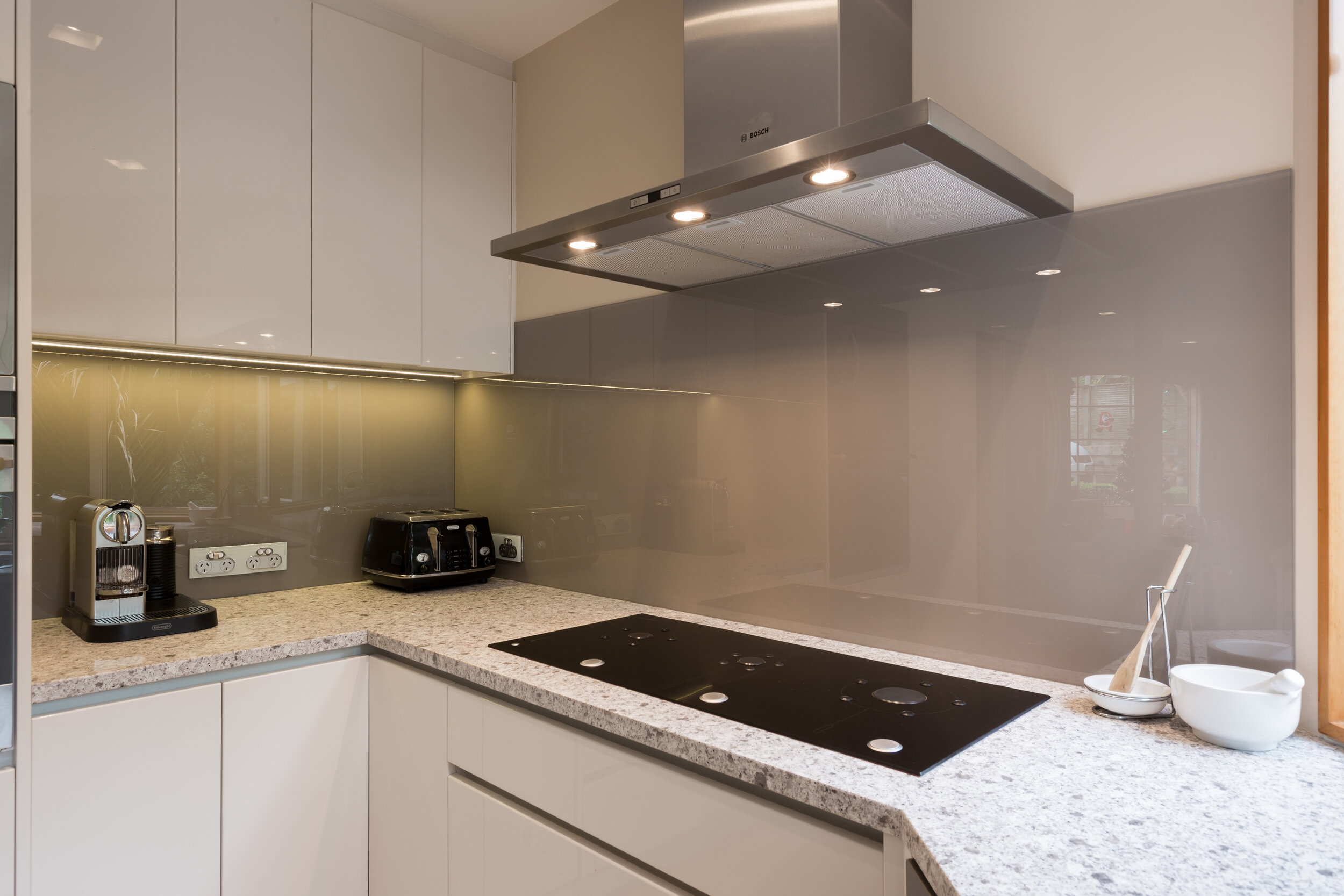 Marble benchtop in white modern kitchen with grey  backpainted glass splashback 