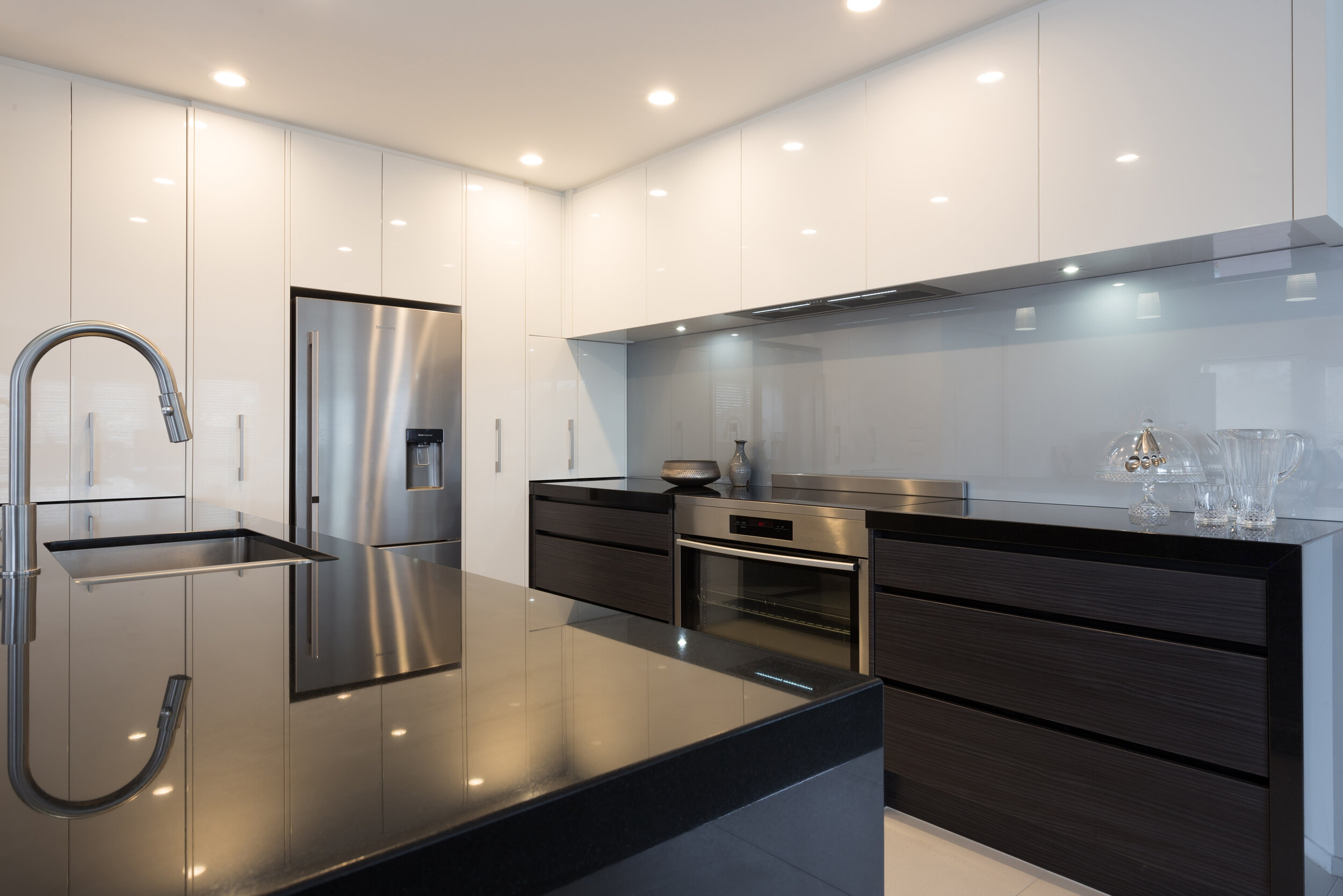 Modern white kitchen with dark benchtop and grey-blue-backpainted glass splashback