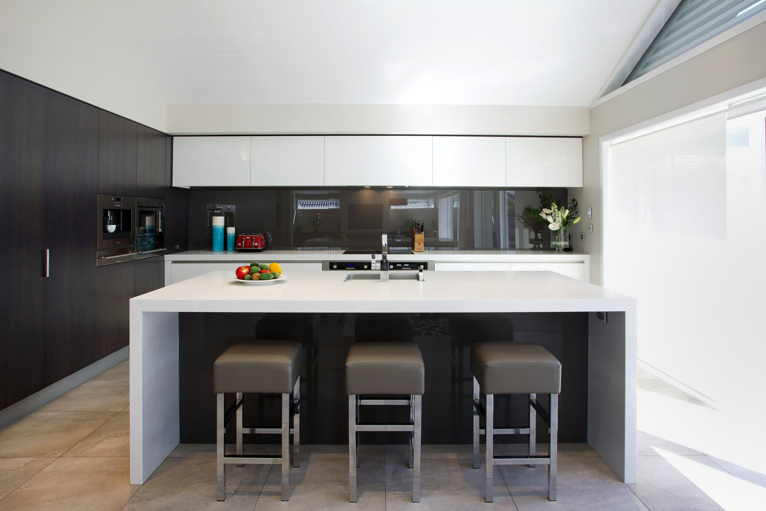Contemporary white kitchen with contrasting dark backpainted glass splashback