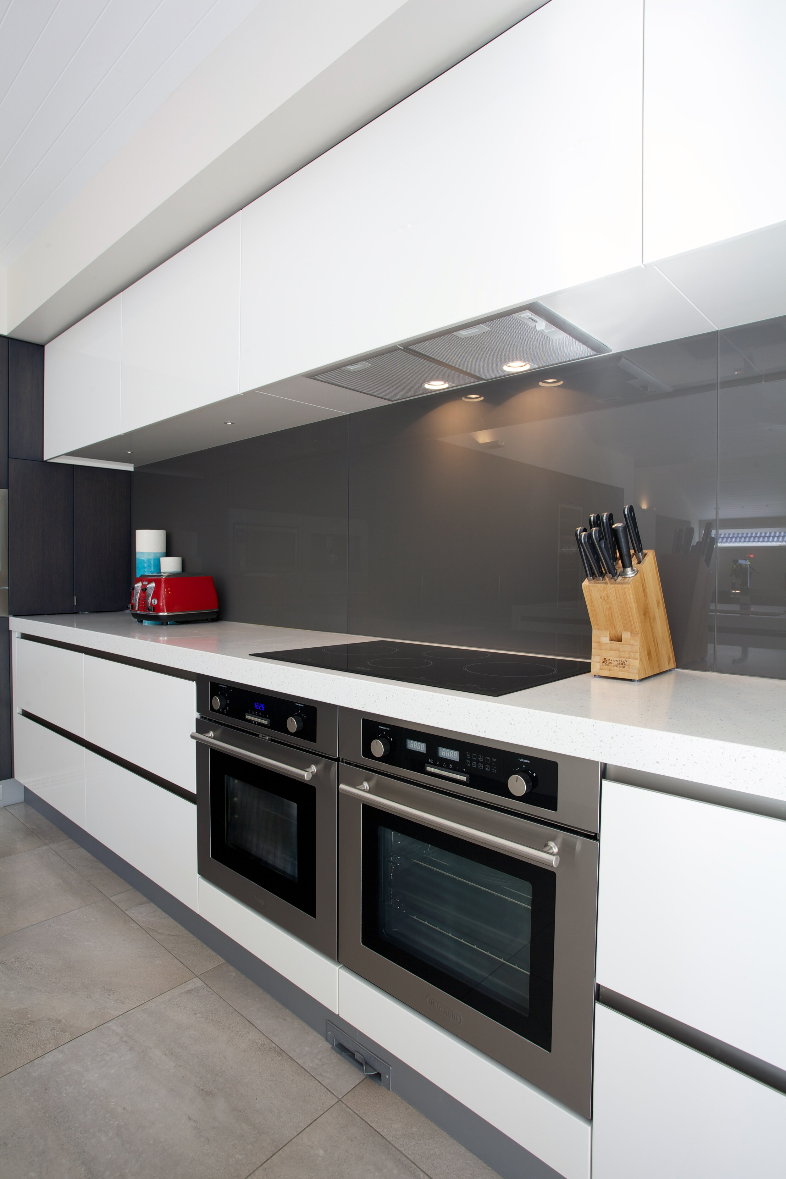 Modern white kitchen with dark contrast backpainted glass splashback