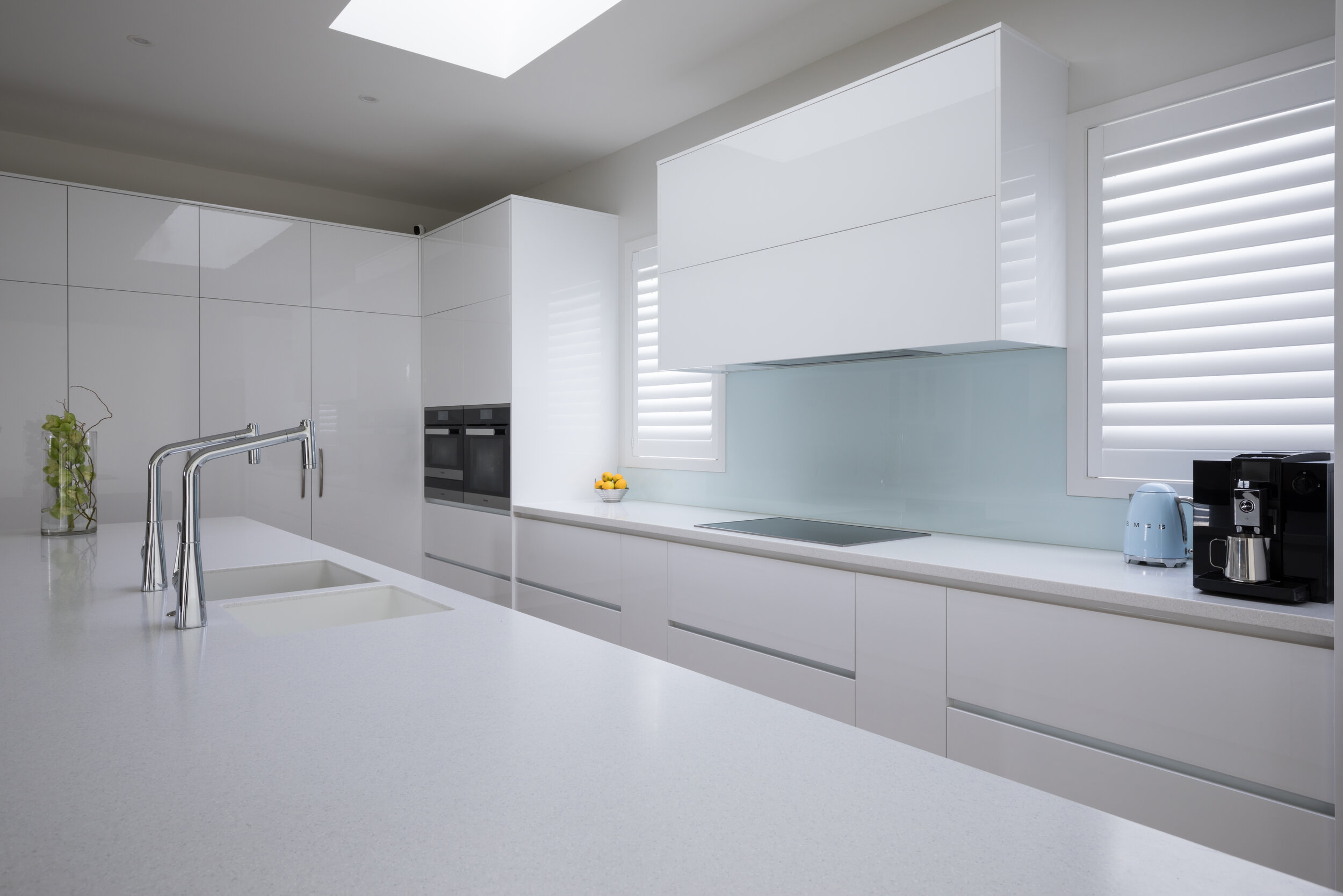 Light blue glass splashback in hi gloss modern white kitchen