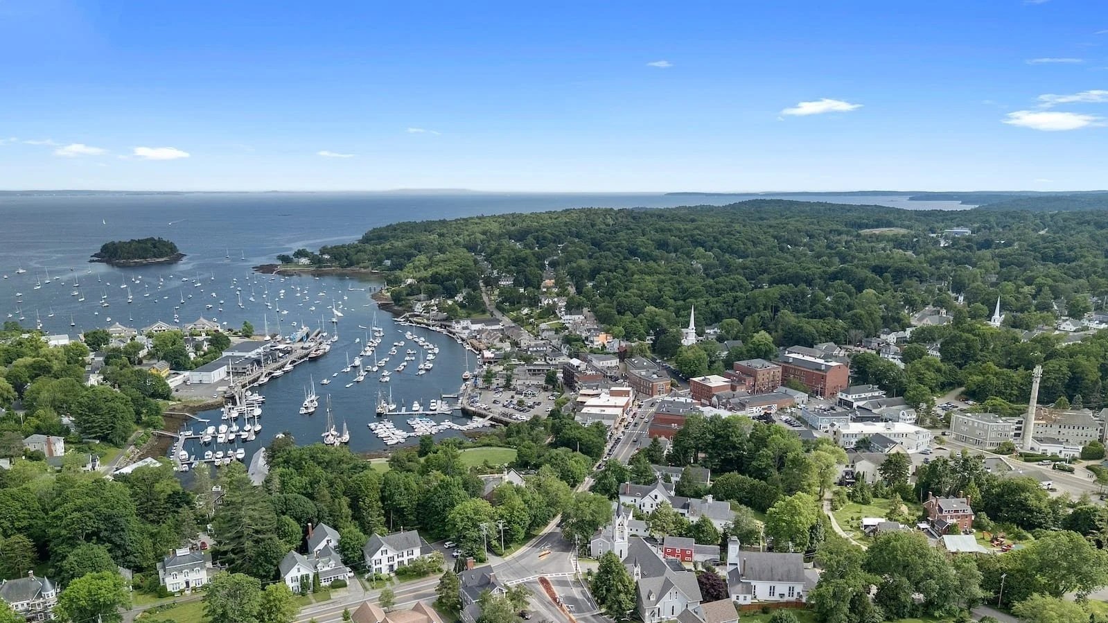 Aerial view of Camden Maine harbor with sailboats, coastline, and downtown village