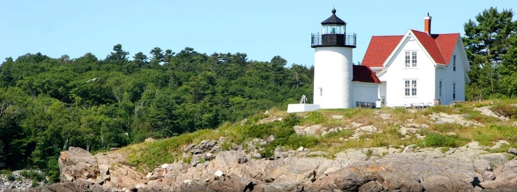 Curtis Island lighthouse near Camden Maine surrounded by rocky coastline and trees