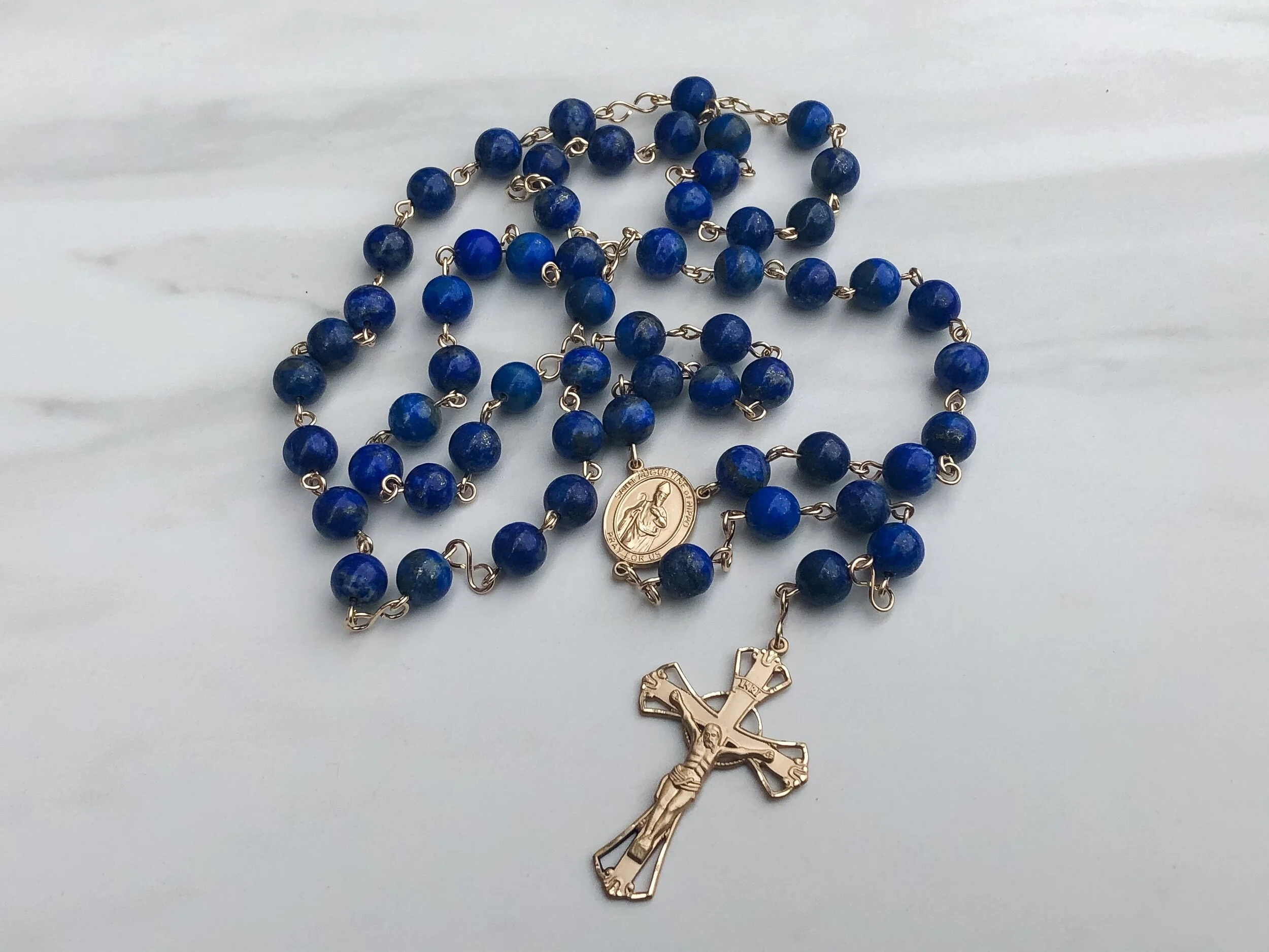 A picture of a lapis lazuli rosary with a gold-filled flared crucifix