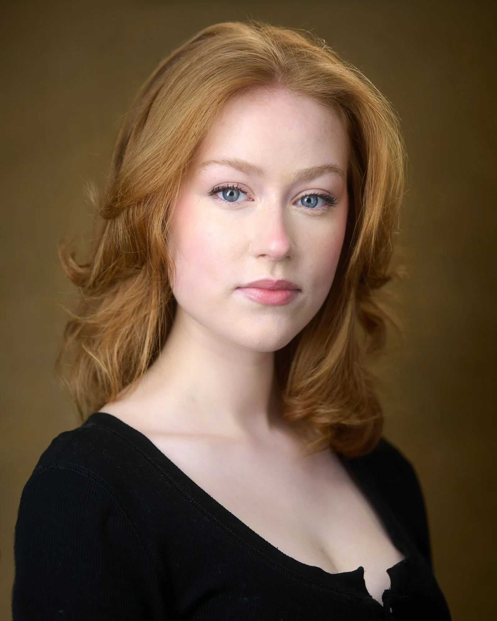 Glasgow based actor headshot of a female against a gold backdrop.