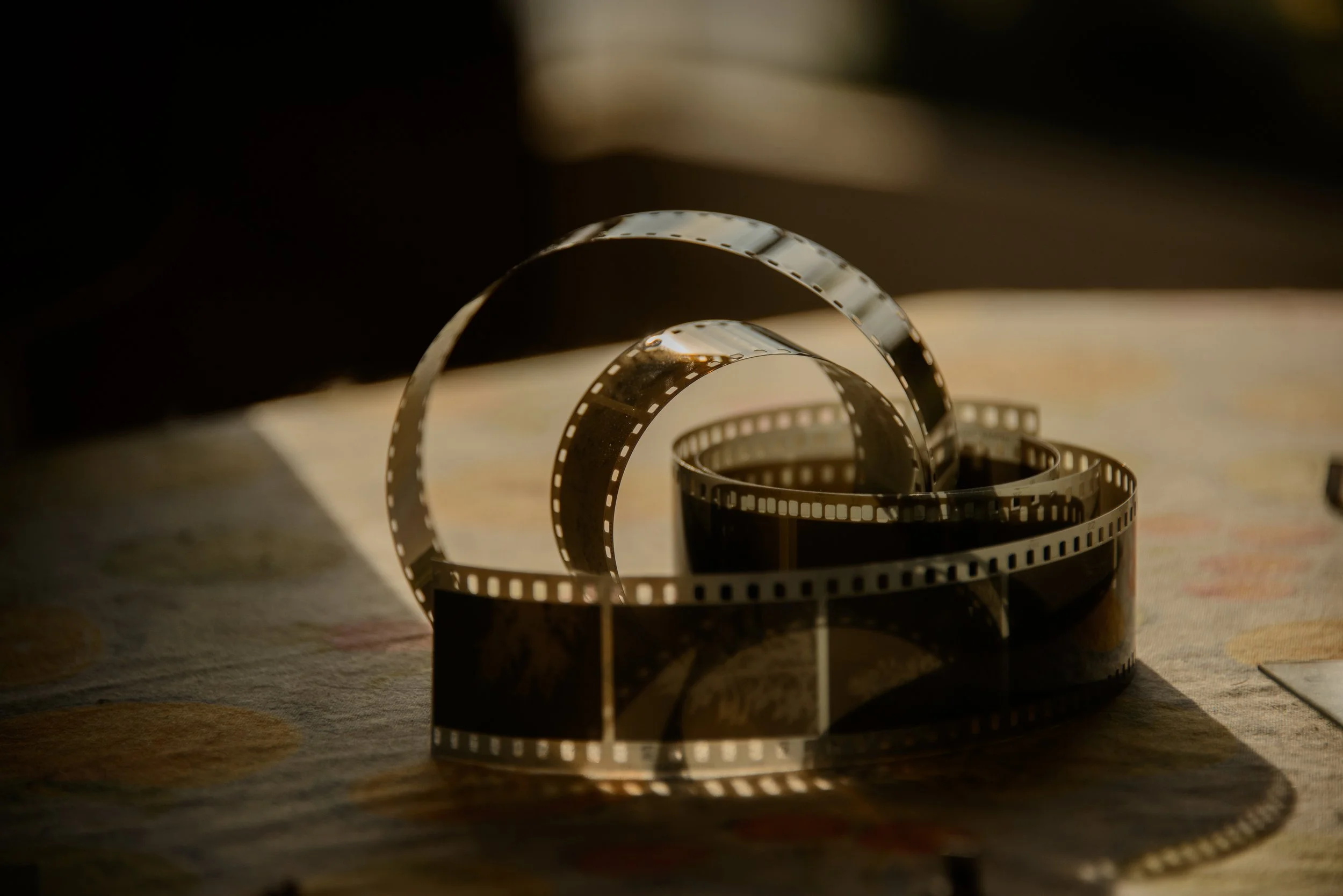 Looped 35 mm motion-picture film negative illustrating film stock as the physical master record that holds tonal range, grain structure, and exposure decisions.