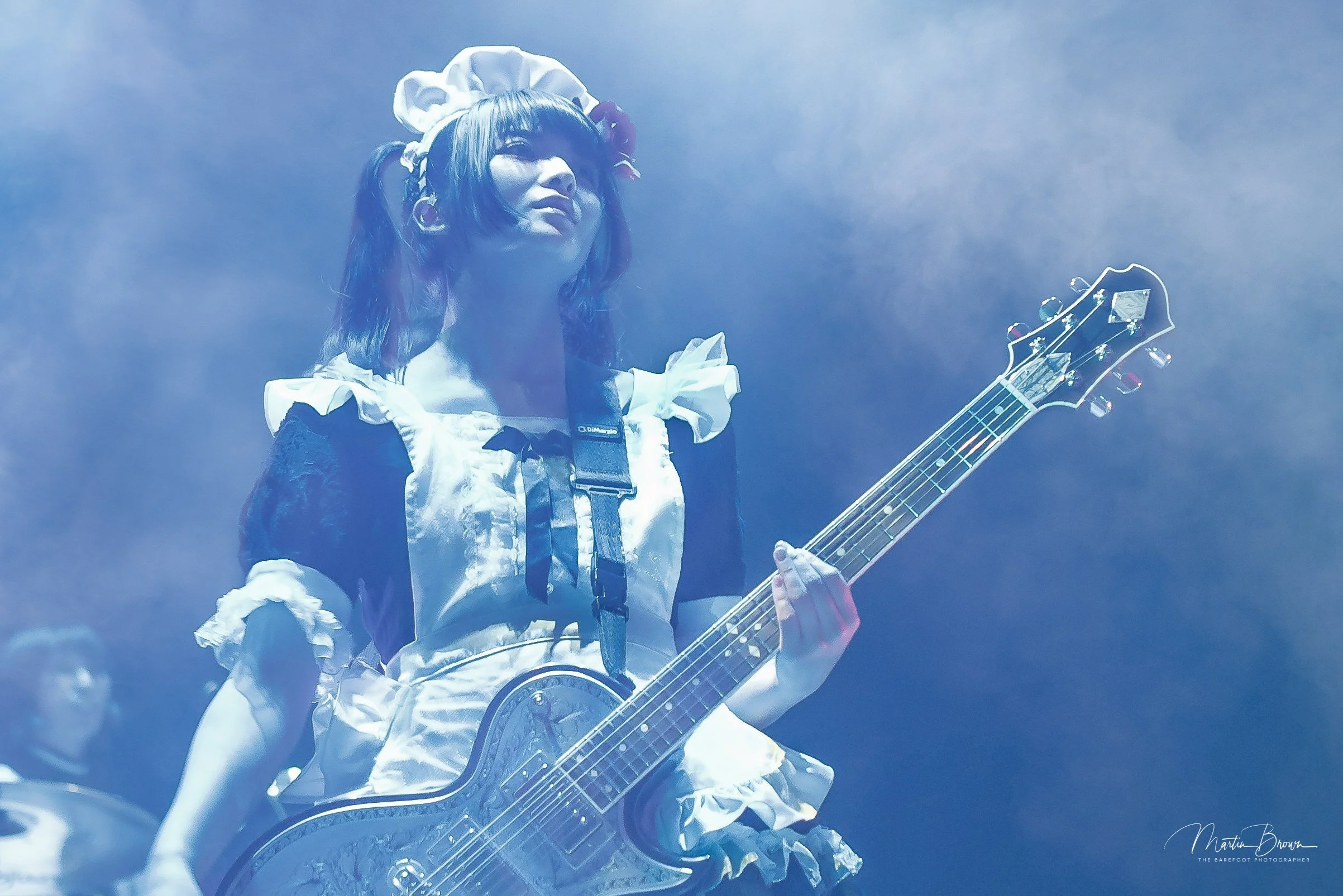 Live concert photograph of a guitarist performing under blue stage lighting, showcasing analogue photography and the creative expertise behind Liquid Light Lab.