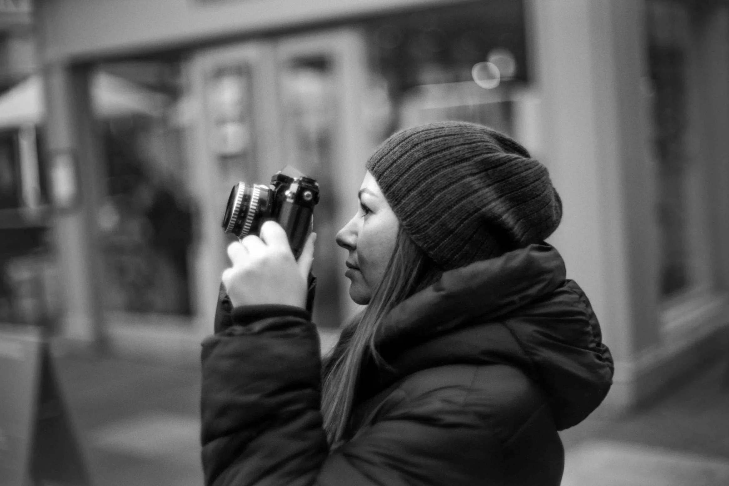 Woman holding a camera in a black and white photograph, used to illustrate specialist 510 Pyro film development at Liquid Light Lab.