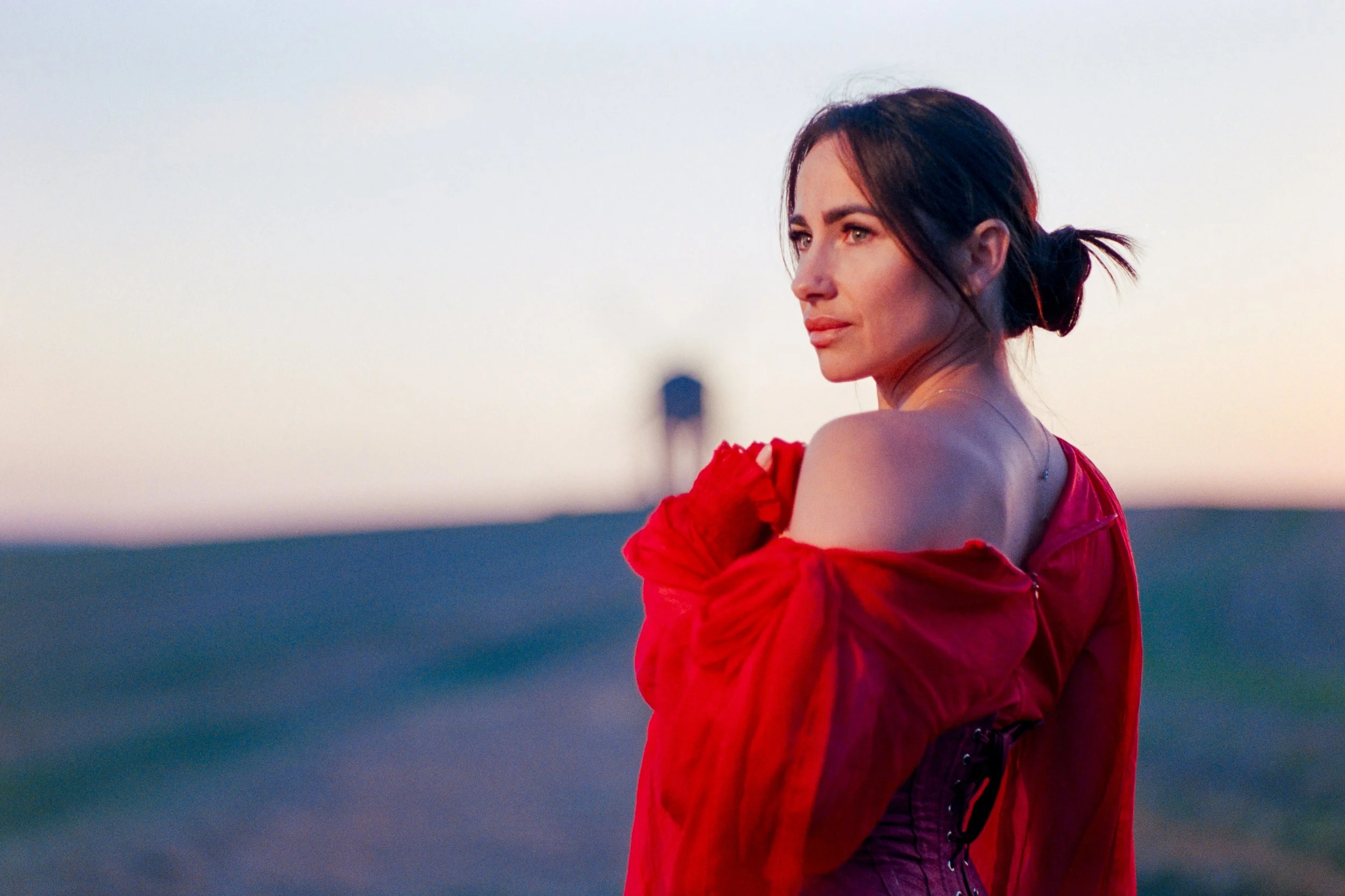 Woman in a red dress photographed outdoors at Chesterton Windmill near Leamington Spa during an on-location portrait session.