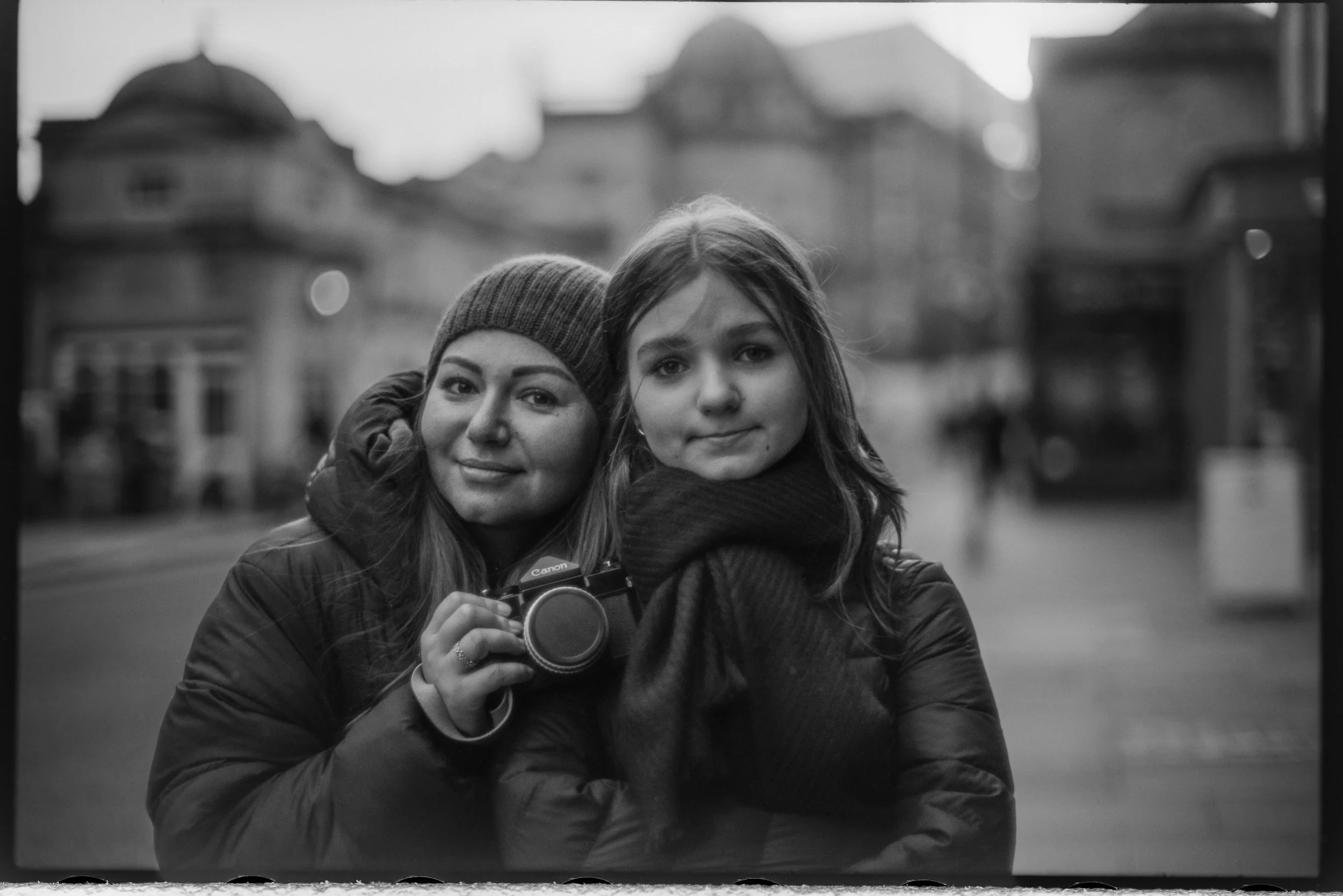 Two women on Bath Street, one holding a Canon film camera, photographed on Babylon 13 at ISO 6 with a Voigtlander 50mm f/1.1 and developed in 510 Pyro.