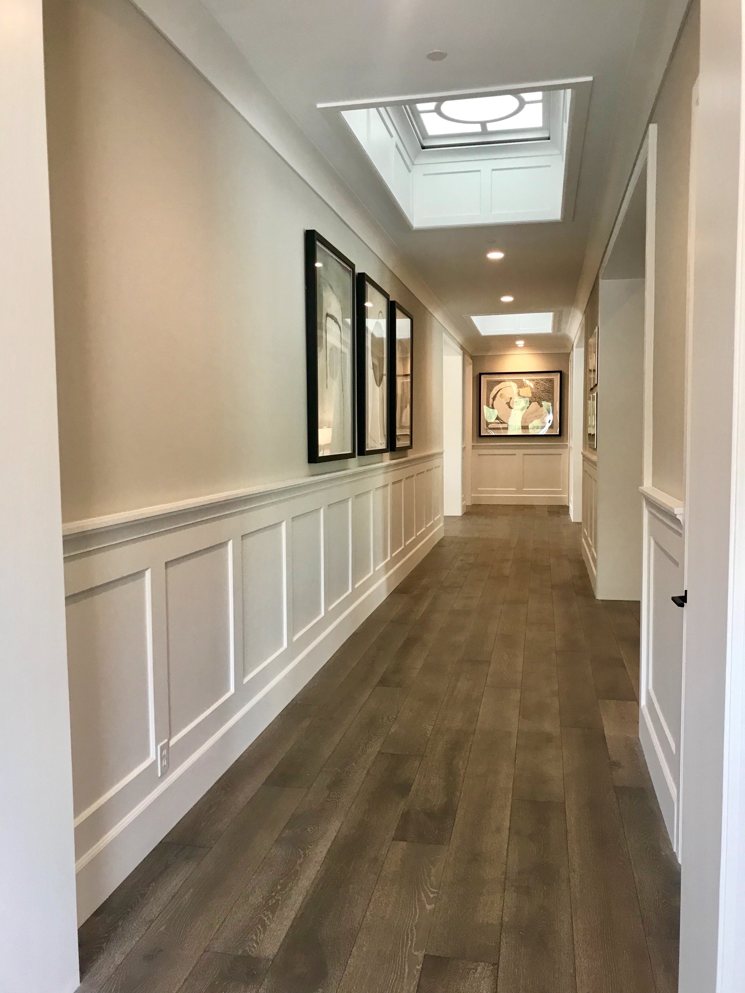 Crisp white wainscoting wraps the main hallway and a series of contemporary artwork dresses up the space.