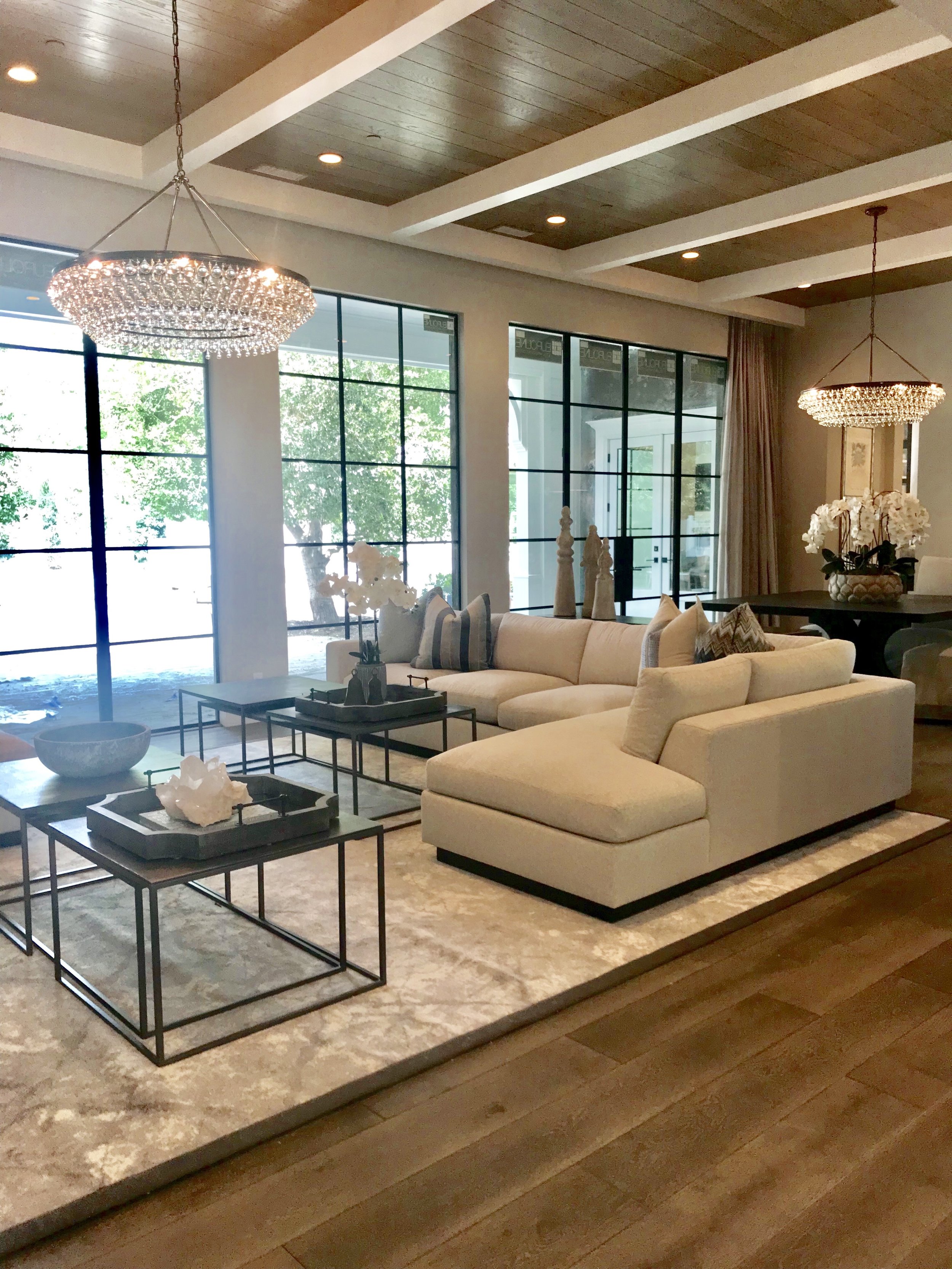 Multiple matte back steel framed doors provide expansive views of the exterior grounds and poolside and the white ceiling beams with warm wood T&G compliment the high ceilings tying in design elements from the entryway.
