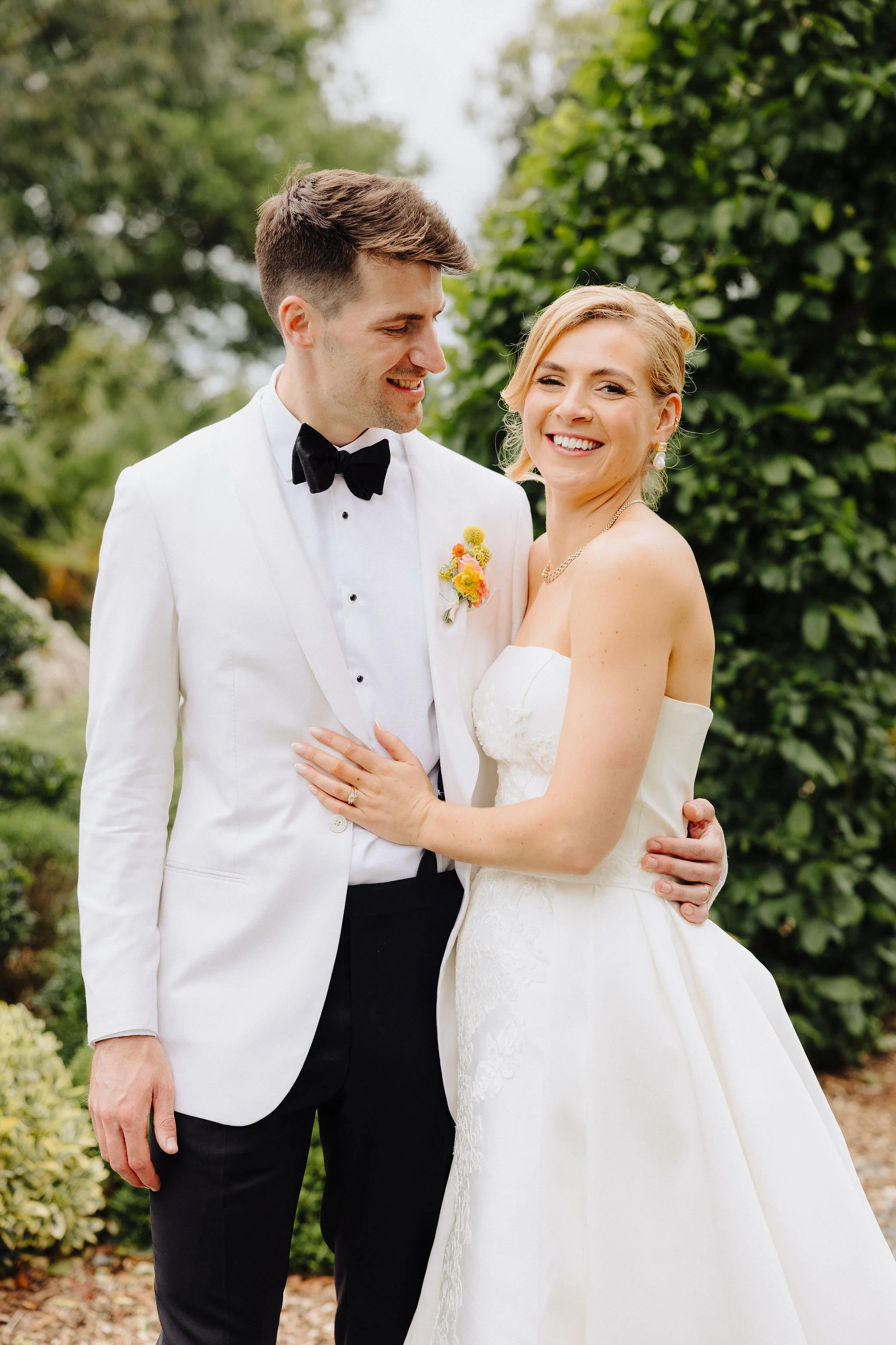 A happy bride and groom smiling and embracing outdoors during their wedding.