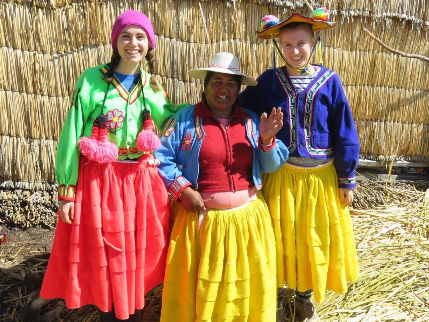 Two Canadian women and a peruvian woman all thre wearing traditionnal peruvian outfits