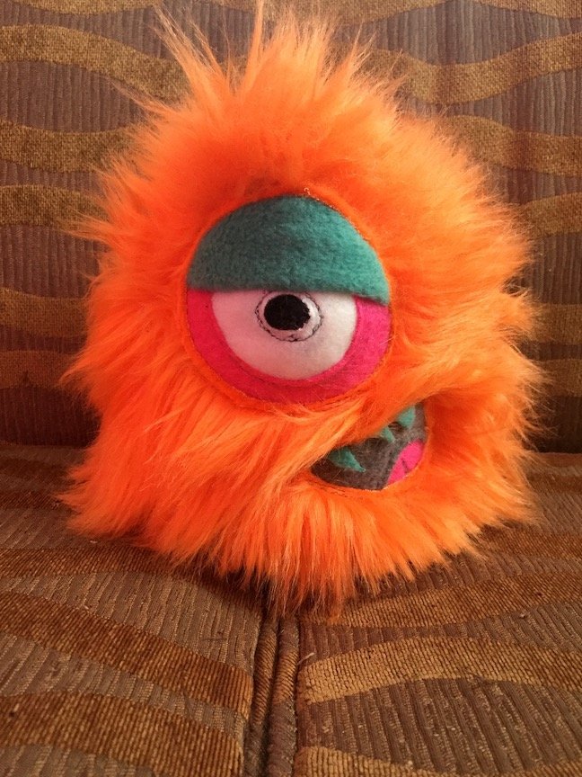 SMALL ORANGE MONSTER WITH ONE SLEEPY EYE AND MOUTH