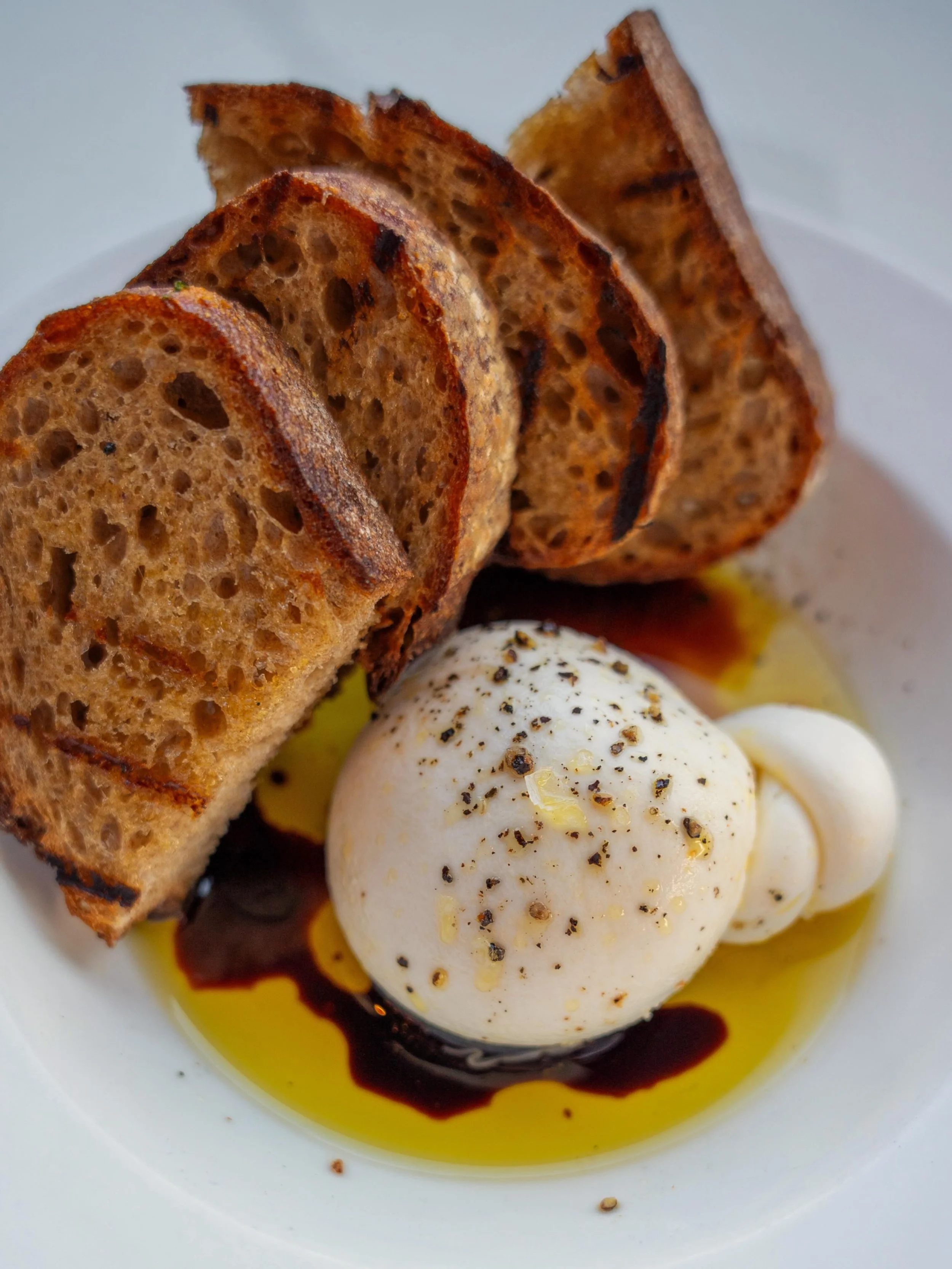 Food and drink exist primarily to serve the purpose of connection. Our Grande Burrata is designed for that - a shared experience for the whole table. It comes with Blue Dog sourdough, estate olive oil, and San Giacomo balsamic vinegar. This shared st