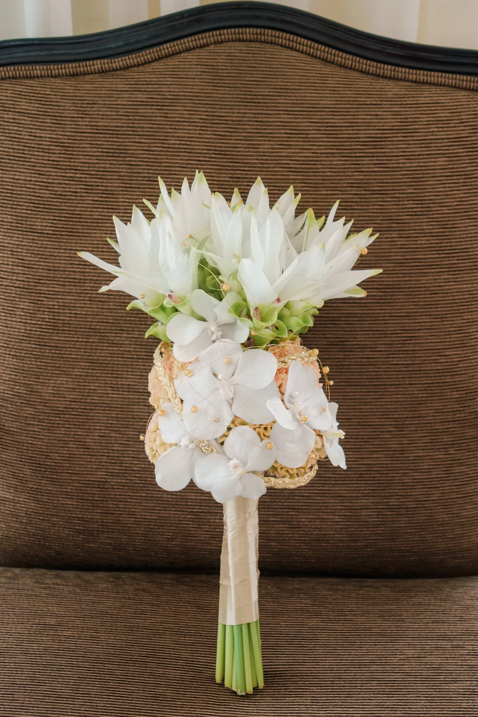 Morsiuskimppu täynnä eksotiikkaa. Morsian ja puku ovat floristille ne lähtökohdat oikeanlaisten kukkien valintaan ja kimpun tyylin suunnitteluun. Tässä kimpussa on joukossa valkoista kurkumaa, orkideoita ja neilikoita. Kimppu on sidottu valtikkamais…