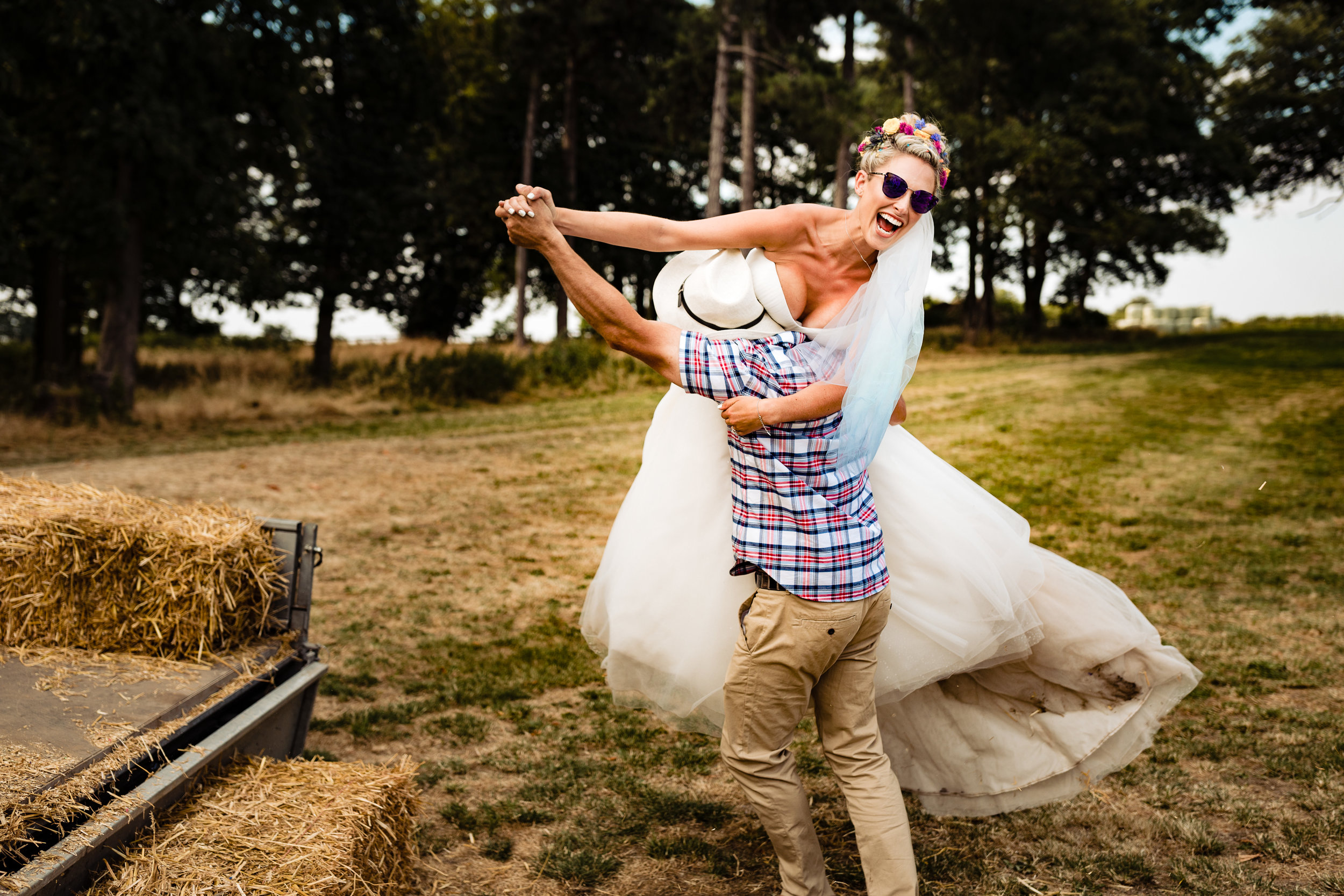 A bride being lifted off a tractor at a farm wedding