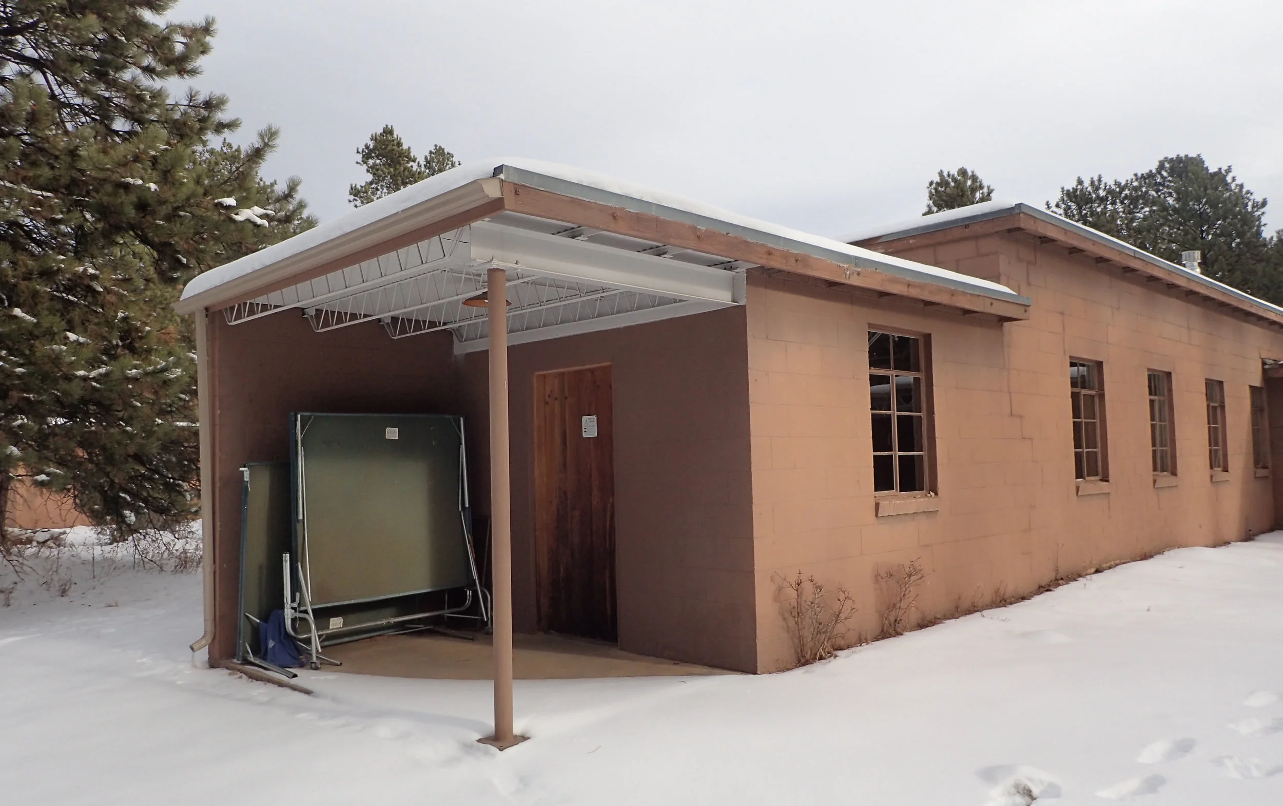 The existing dorm is a simple concrete masonry structure with a flat roof supported by exposed, open-webbed metal joists.  The solid north wall blocked the view from the property's northwest entrance.