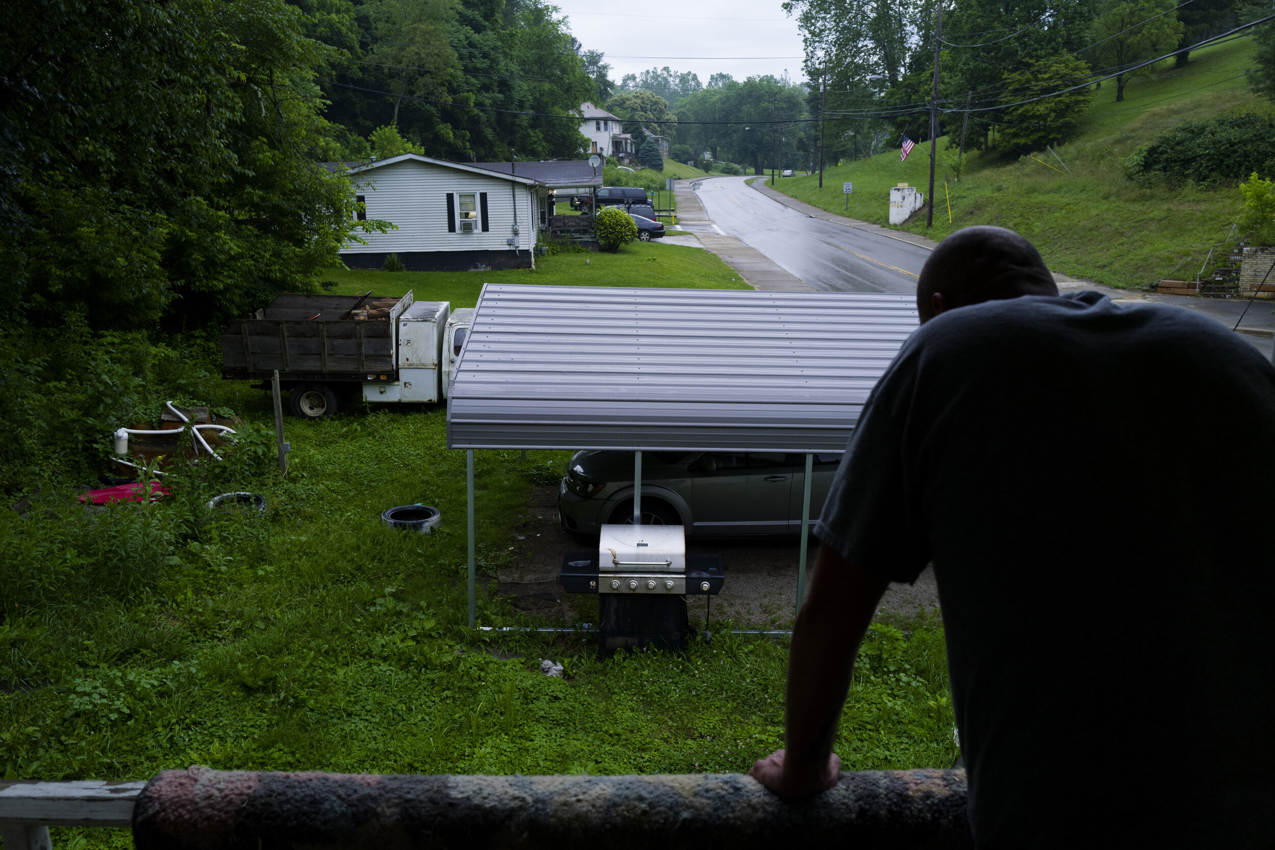  Ben looks out to the road off of his balcony in New Straitsville, Ohio, dry heaving from stomach pain he gets from anxiety on June 21, 2021. The night before last on Father’s Day, Reuben ran off and reconnected with Daniel L. McKee, a “dangerous dru
