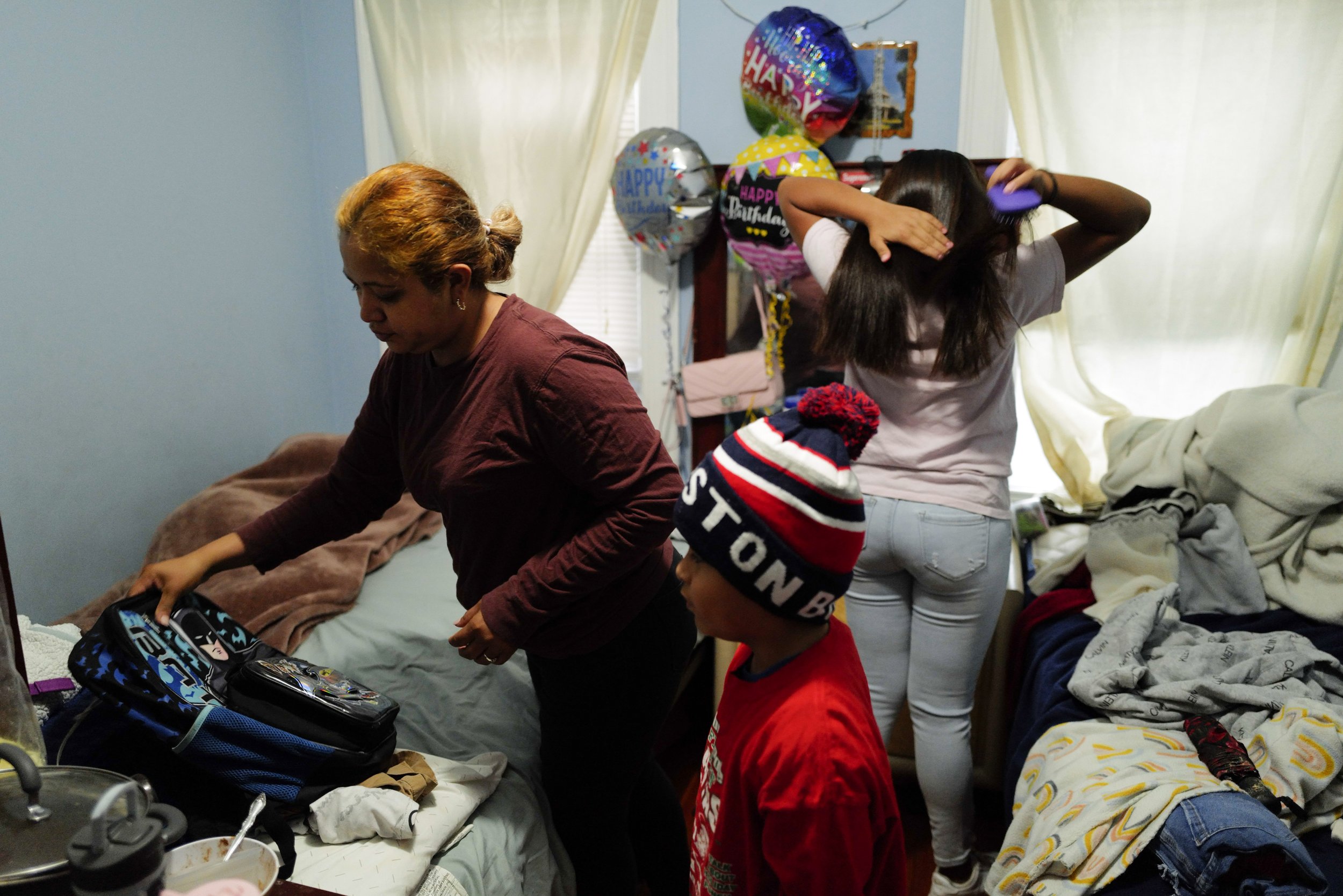  Teresa (left) helps pack her son, Raul Alexis’s (center), 6, school bag while Manuel’s daughter, Fernanda Aimee (right), 12, combs her hair in the early morning before school inside the shared room Manuel and Teresa rent in their old residence in So