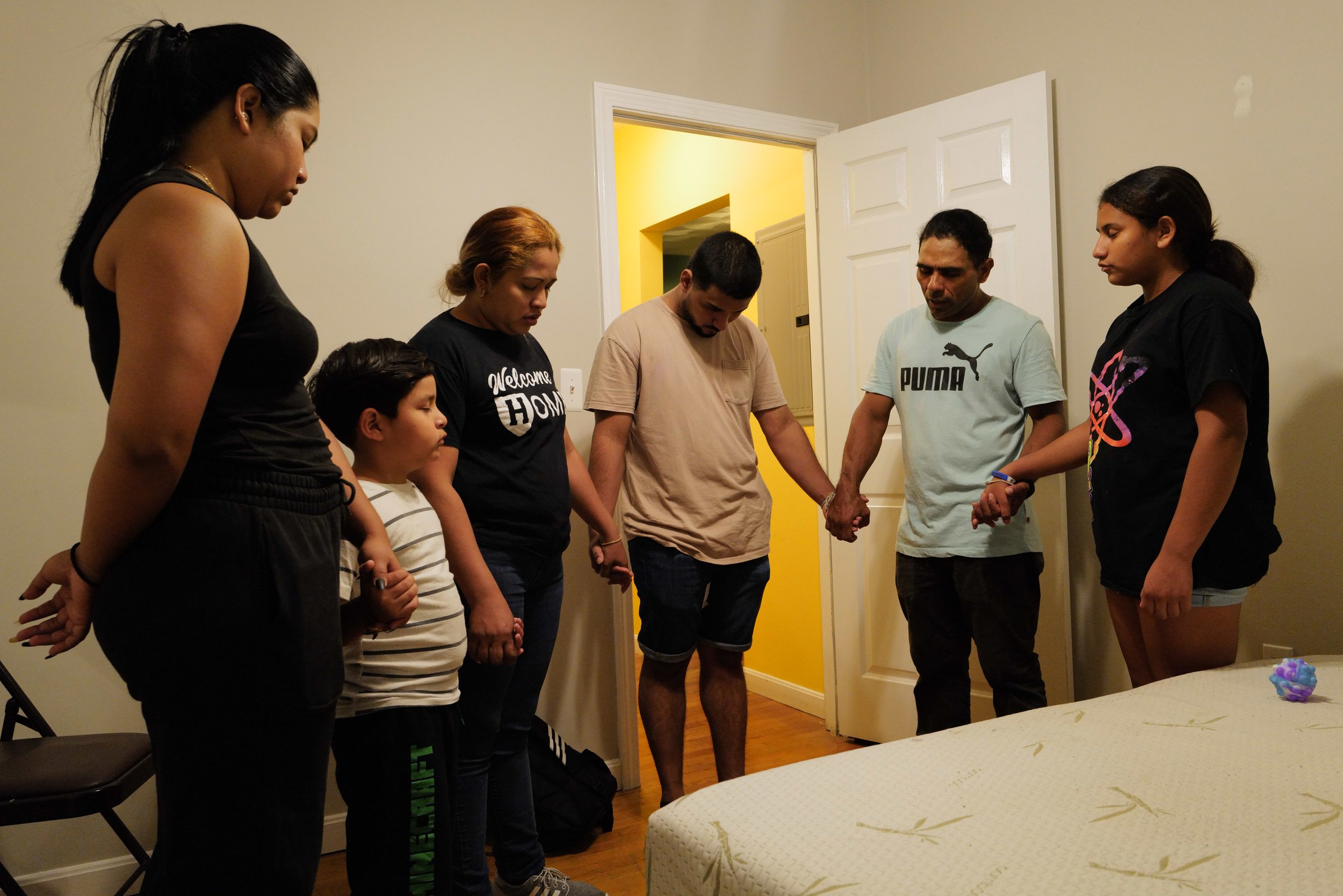  Teresa’s children Kairy Lisbeth, 17 and Raul Alexis, 6, Teresa, Manuel’s son Melquencedec Anthony, 21, Manuel and Manuel’s daughter, Fernanda Aimee, 12, hold hands in prayer after moving into their new more spacious home in Somerville, Mass. in the 
