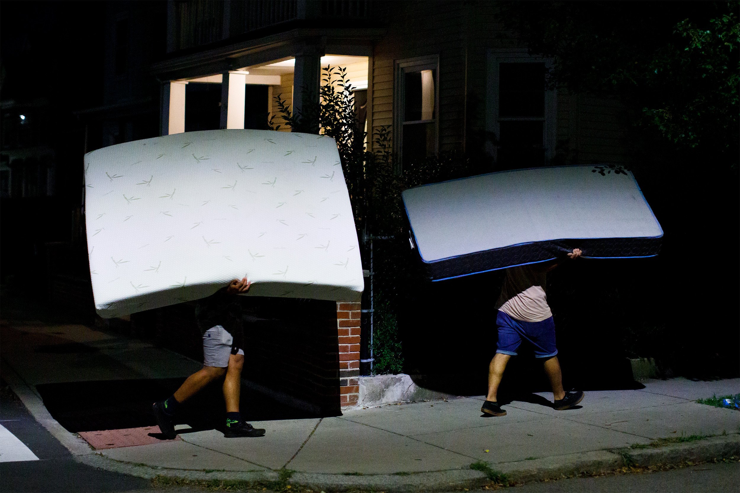  Manuel’s son Melquencedec Anthony (right) and family friend Hector Henriquez (left)  carry a mattresses though the streets of Somerville, Mass. to the new residence early in the morning of Sept. 2, 2022.  