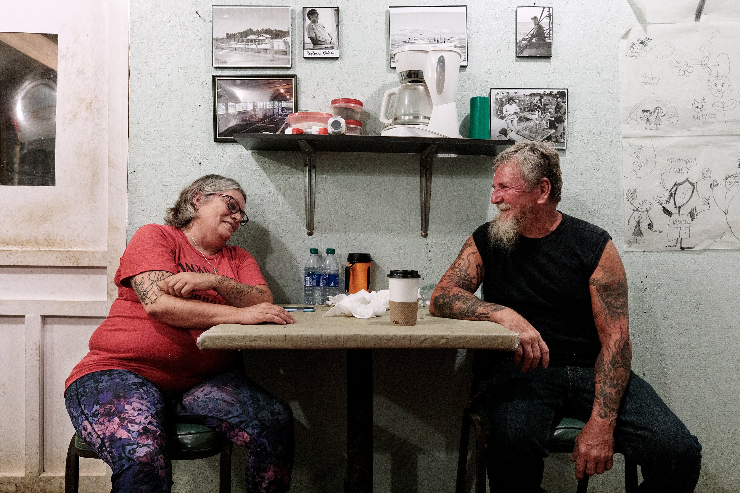  Clyde “Butch” Walters and his wife MaeBelle sit for a portrait in their crab shanty. Family photos and their children’s drawings hang above them. The couple have sold blue crabs together for 38 years, but between their three children, “none of them 