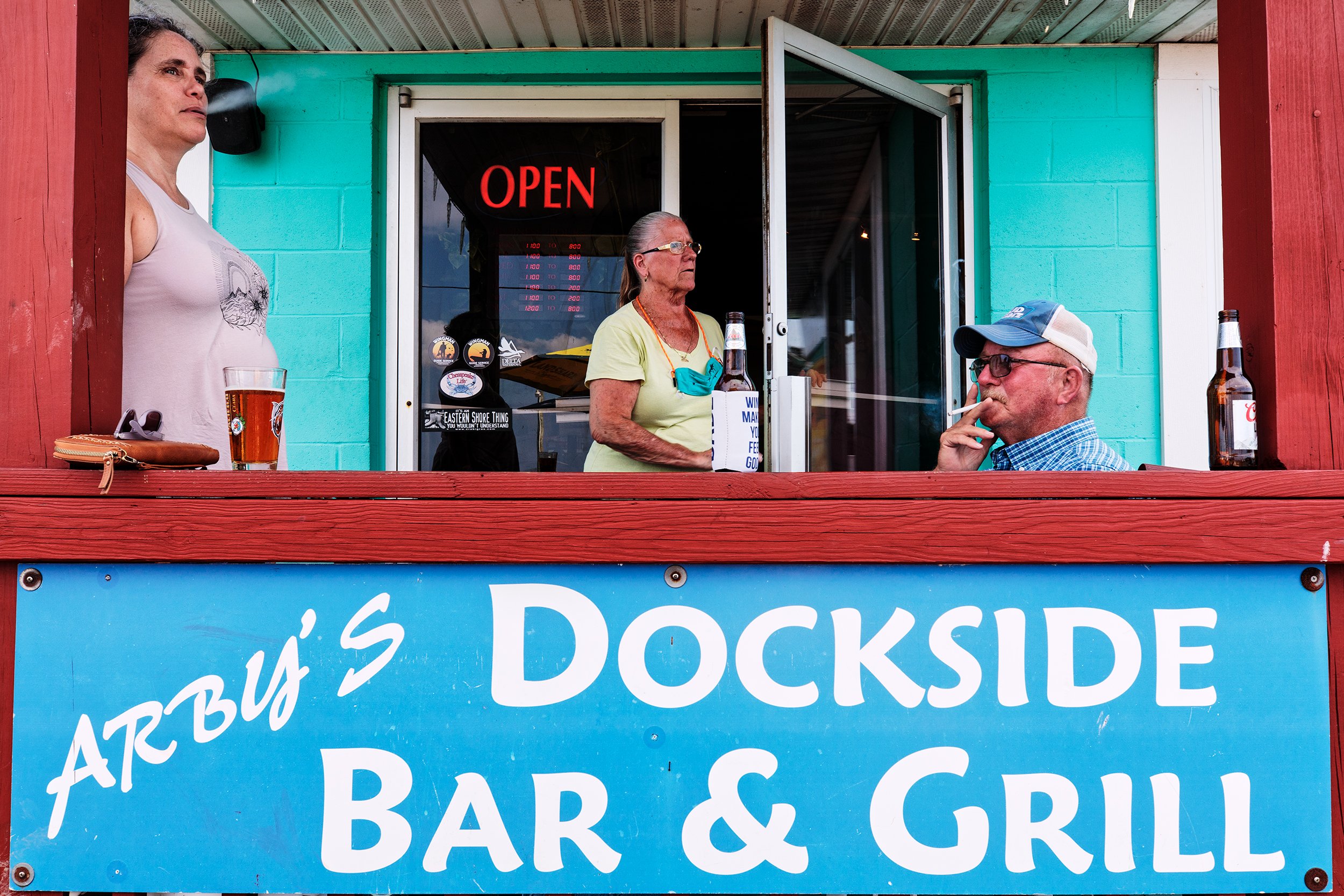  Arby Holland smokes a cigarette on the patio with Sharlene Thornton, while his wife Debbie peaks outside to check on customers. Like many fishing towns, Arby’s is the only location on Deal Island where locals can get food and supplies. Since the pan