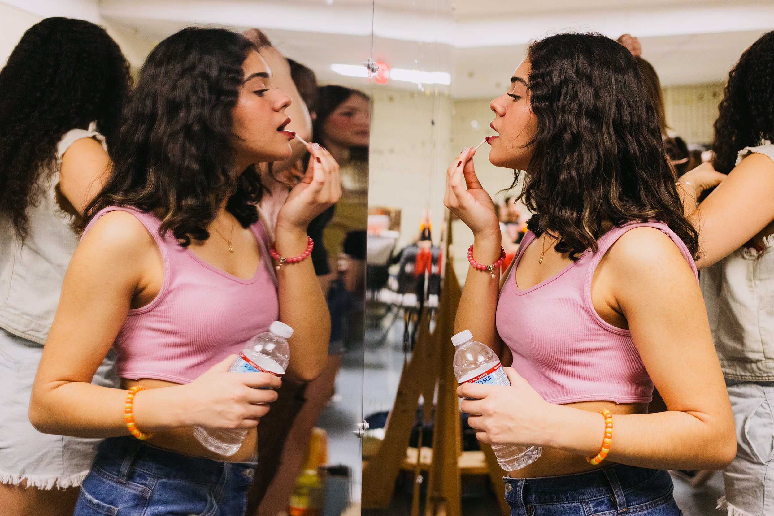  Valery Echavarria applies lipstick in a mirror backstage before the performance of “In the Heights” where she plays  Luisa, a Salon Lady,  at Revere High School on April 12, 2023. 