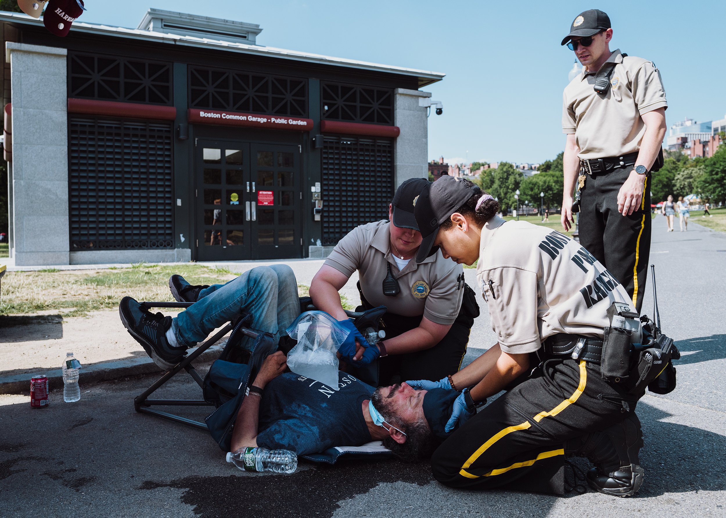  Ranger Emily Wright (center) and Ranger Simone Joseph (right) respond to a man who collapsed from heat stroke at a souvenir stand in the Boston Common, the second incident of the day, on July 23, 2022. Temperatures reached into the high 90’s, increa