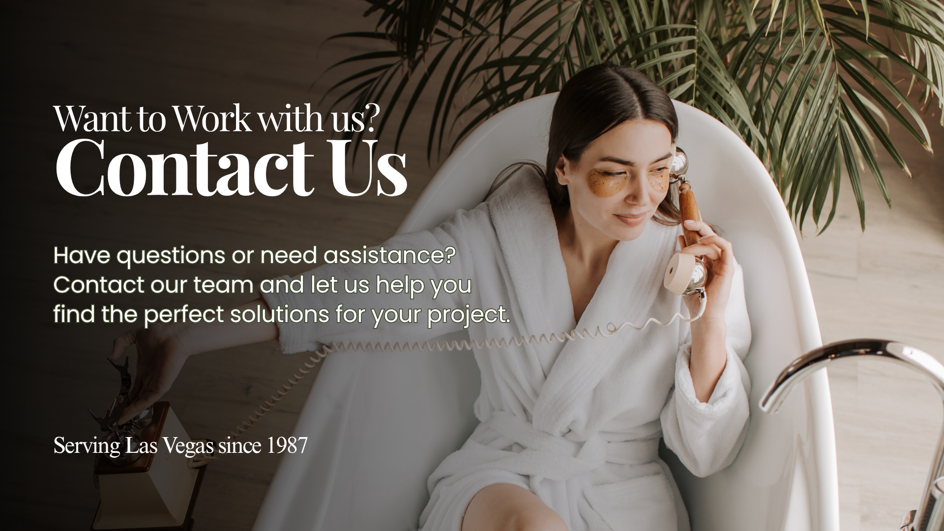 Woman in a white robe sitting in a freestanding bathtub and speaking on a vintage phone, with greenery and a Contact Us message for European Bath | Kitchen | Tile & Stone.