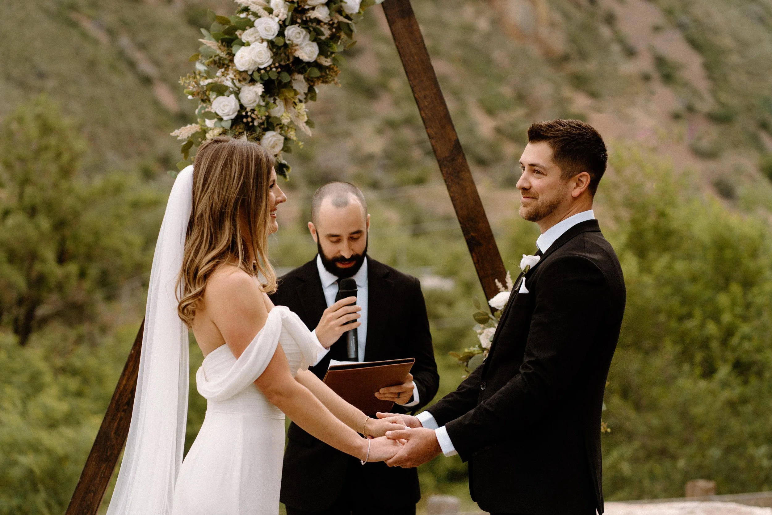 Bride and groom holding hands during ceremony on wedding day in Golden Colorado