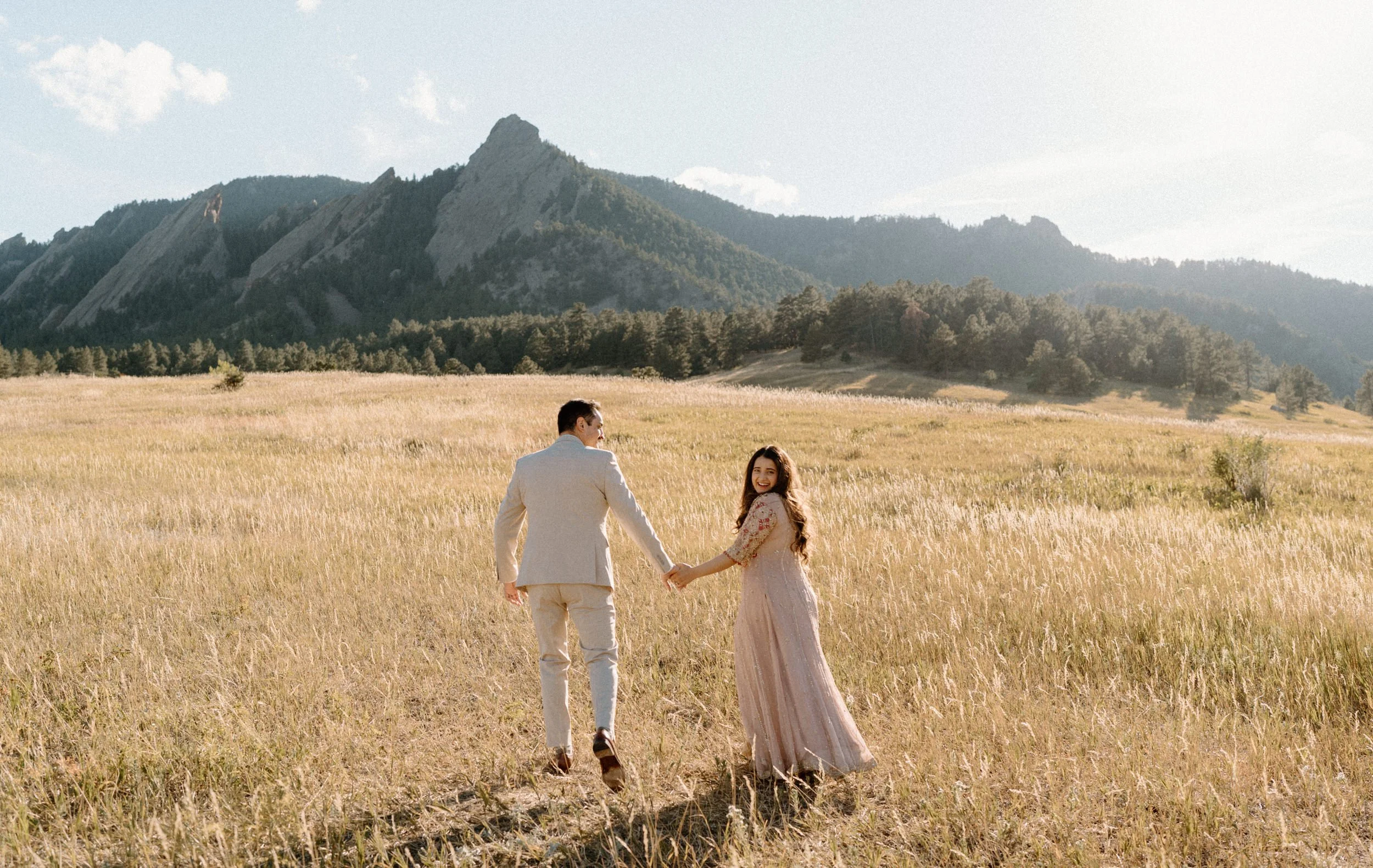Couple hiking in Boulder Colorado during engagement session while fiancée smiles at camera