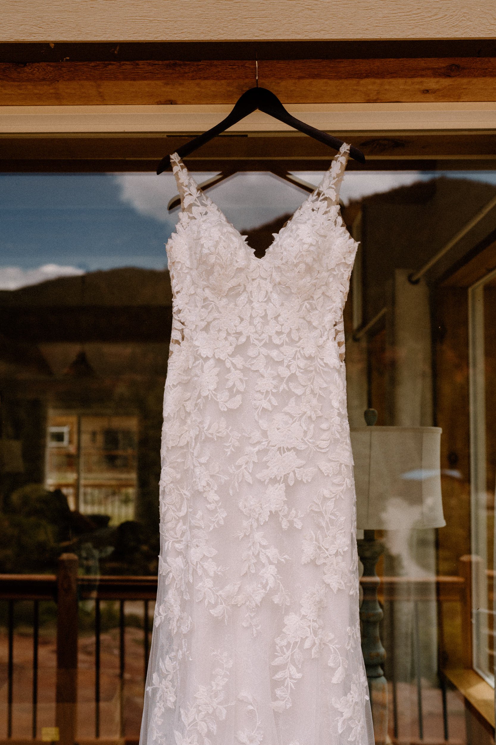 A white wedding dress hangs from the door