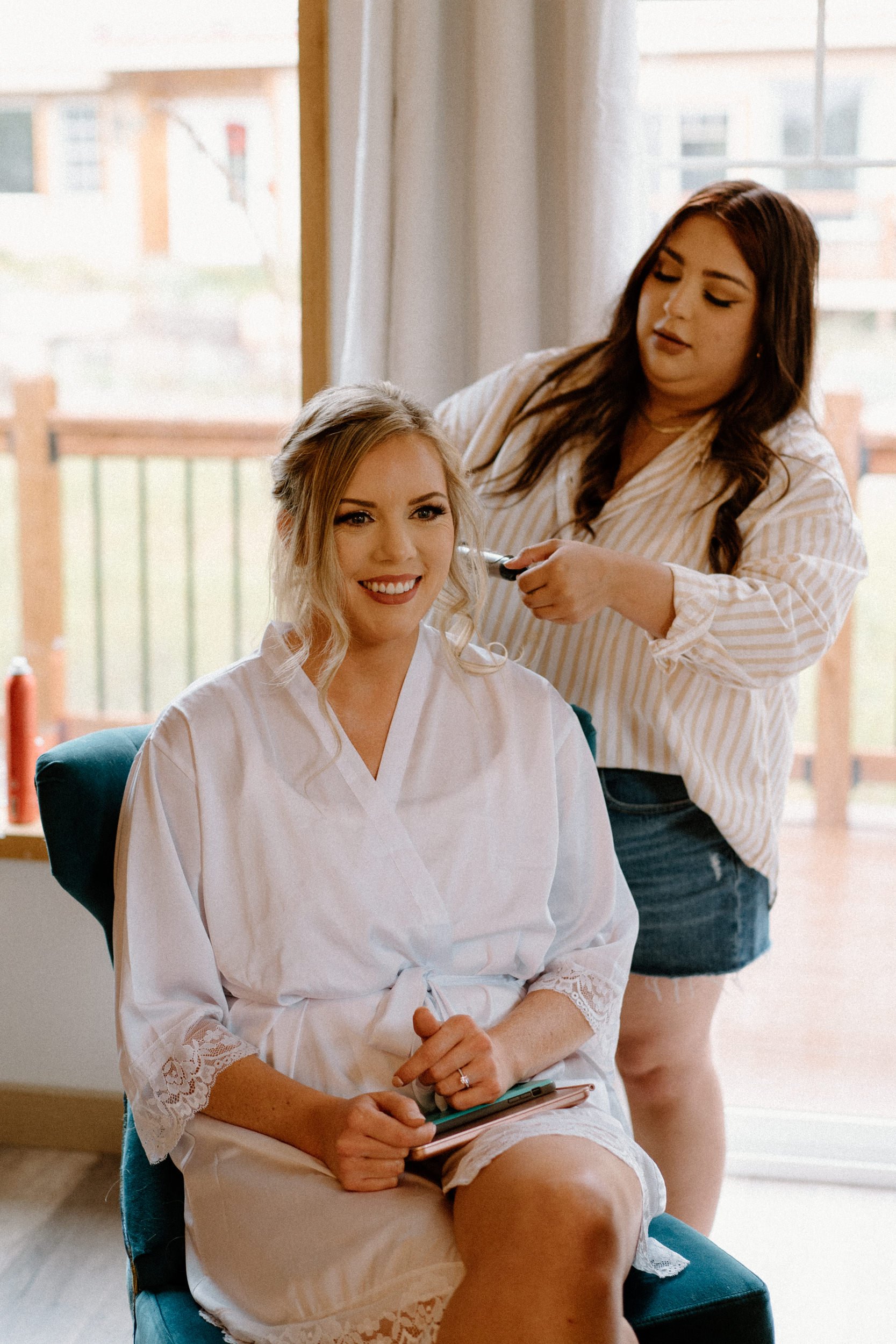 A hairstylist styles the bride's hair