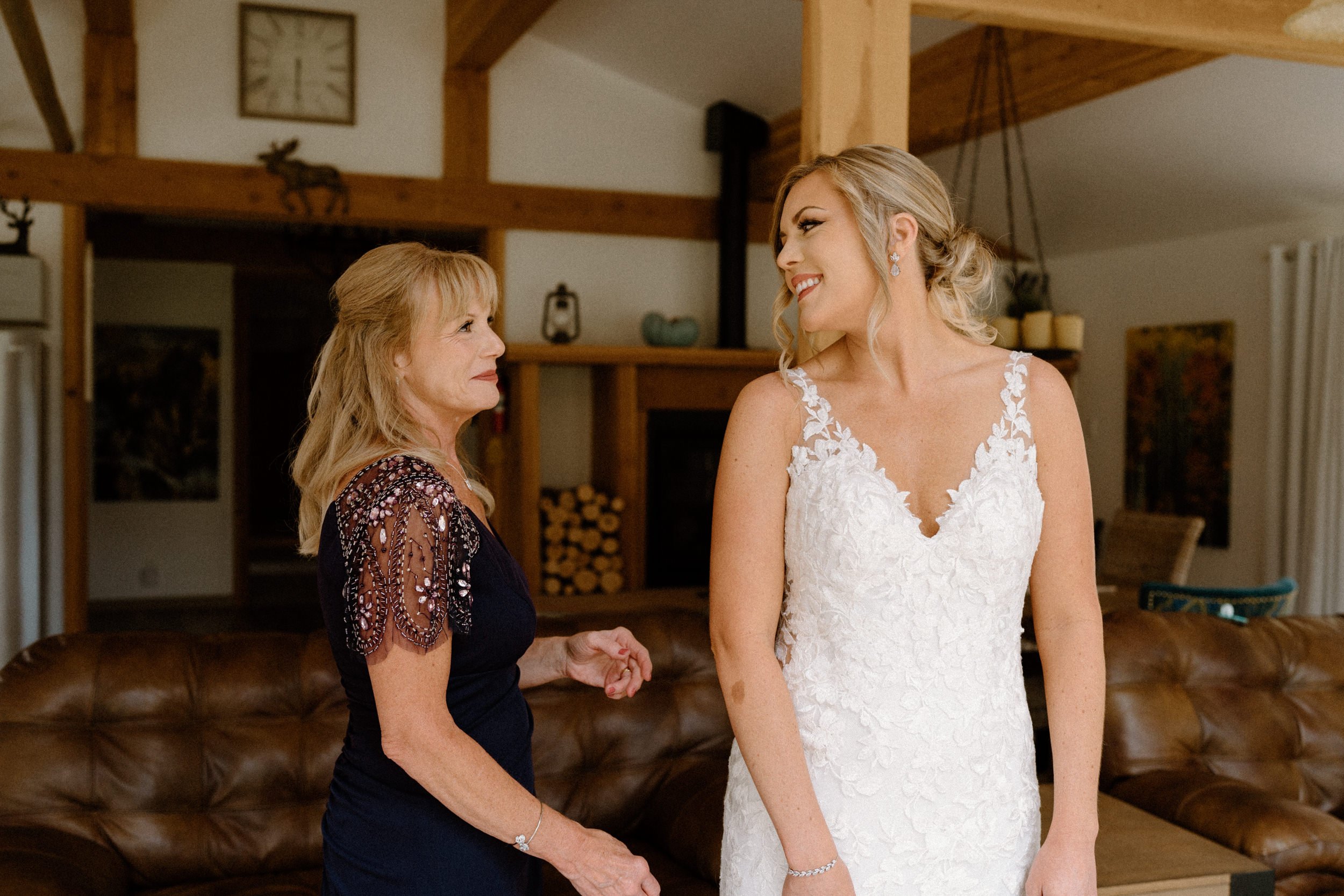 Bride and her mother smile at each other while getting ready