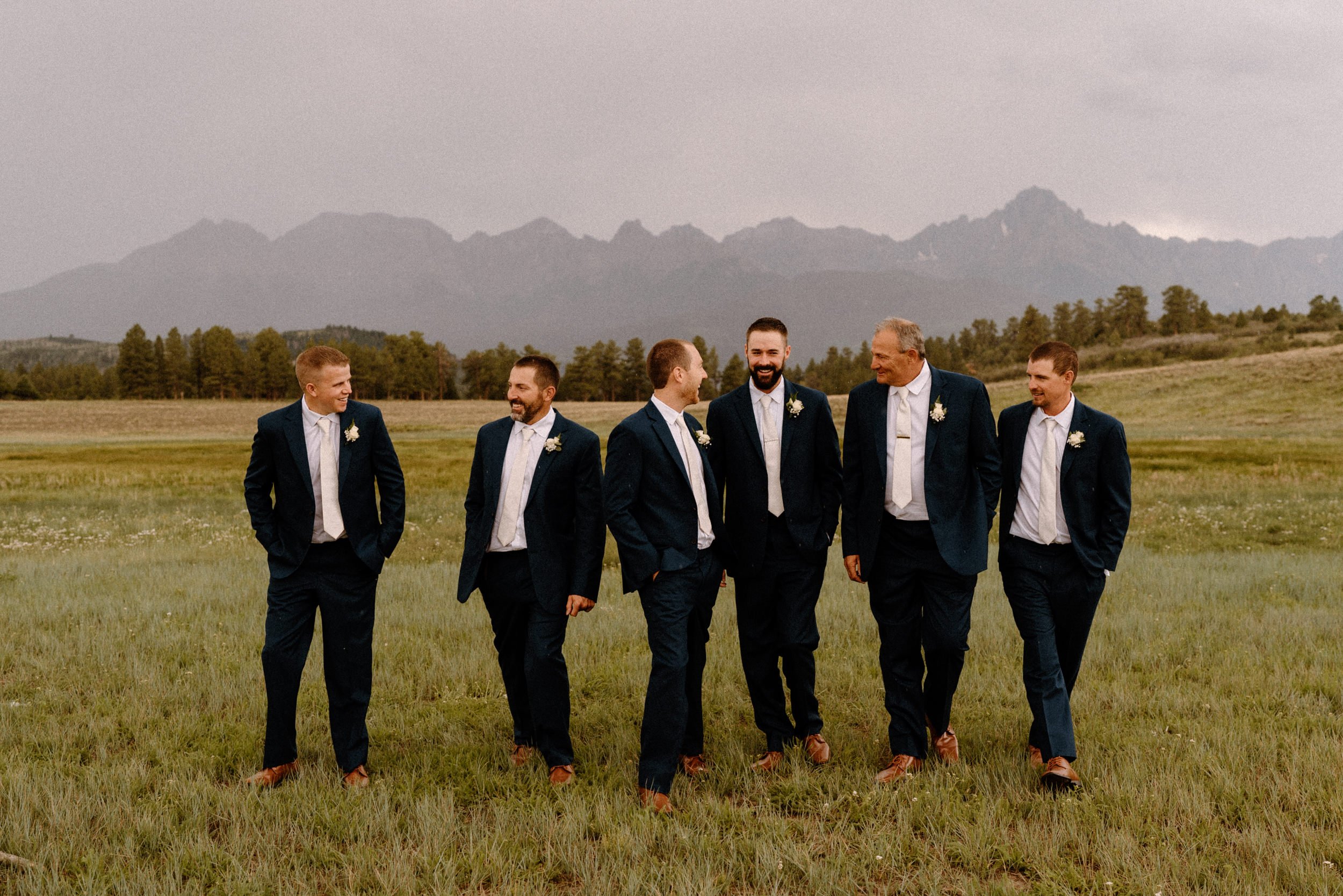 Groom and groomsmen laugh together outside at Top of the Pines in Ridgway, CO