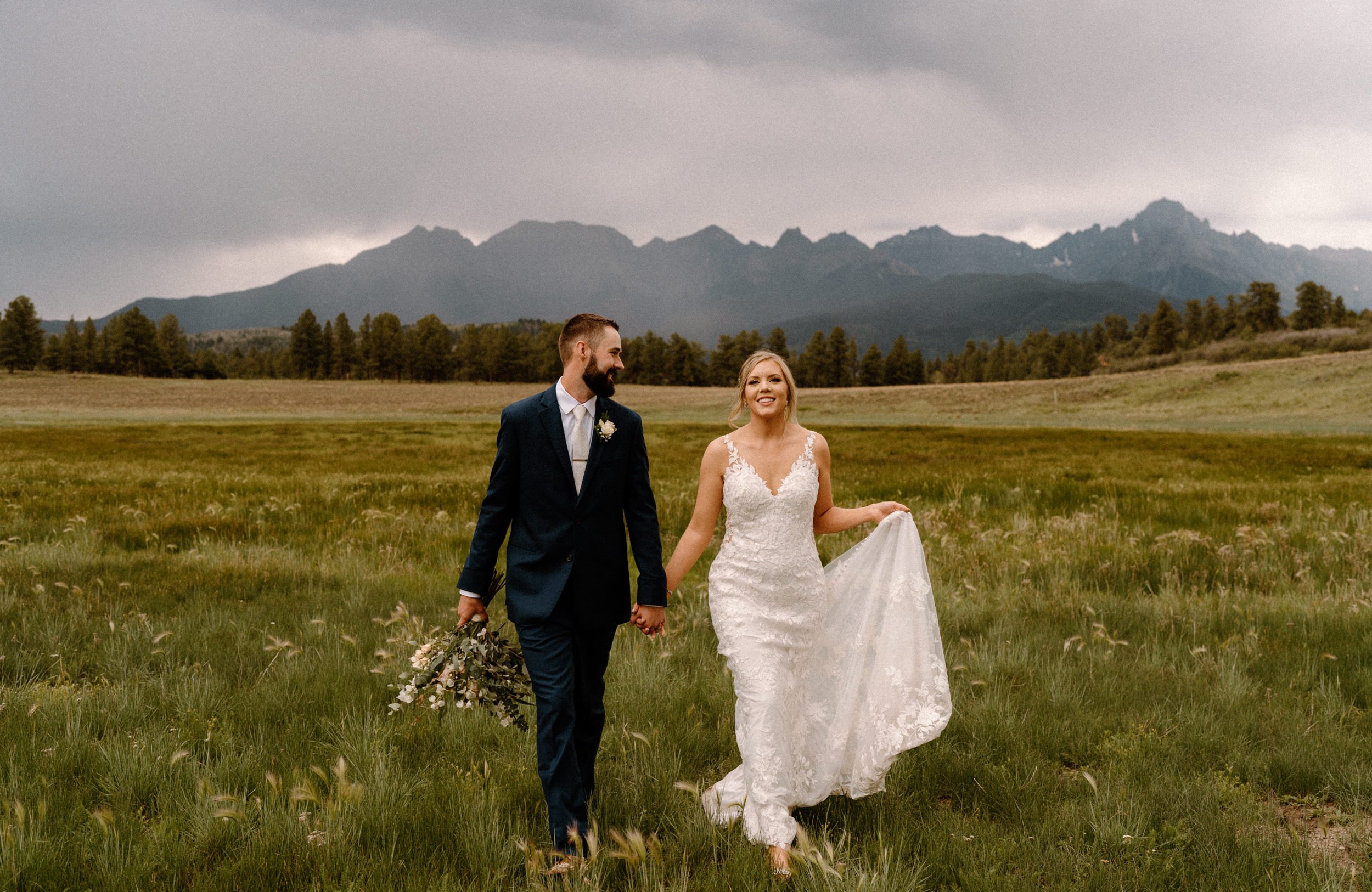 Bride and groom walk through valley at Top of the Pines in Ridgway, CO