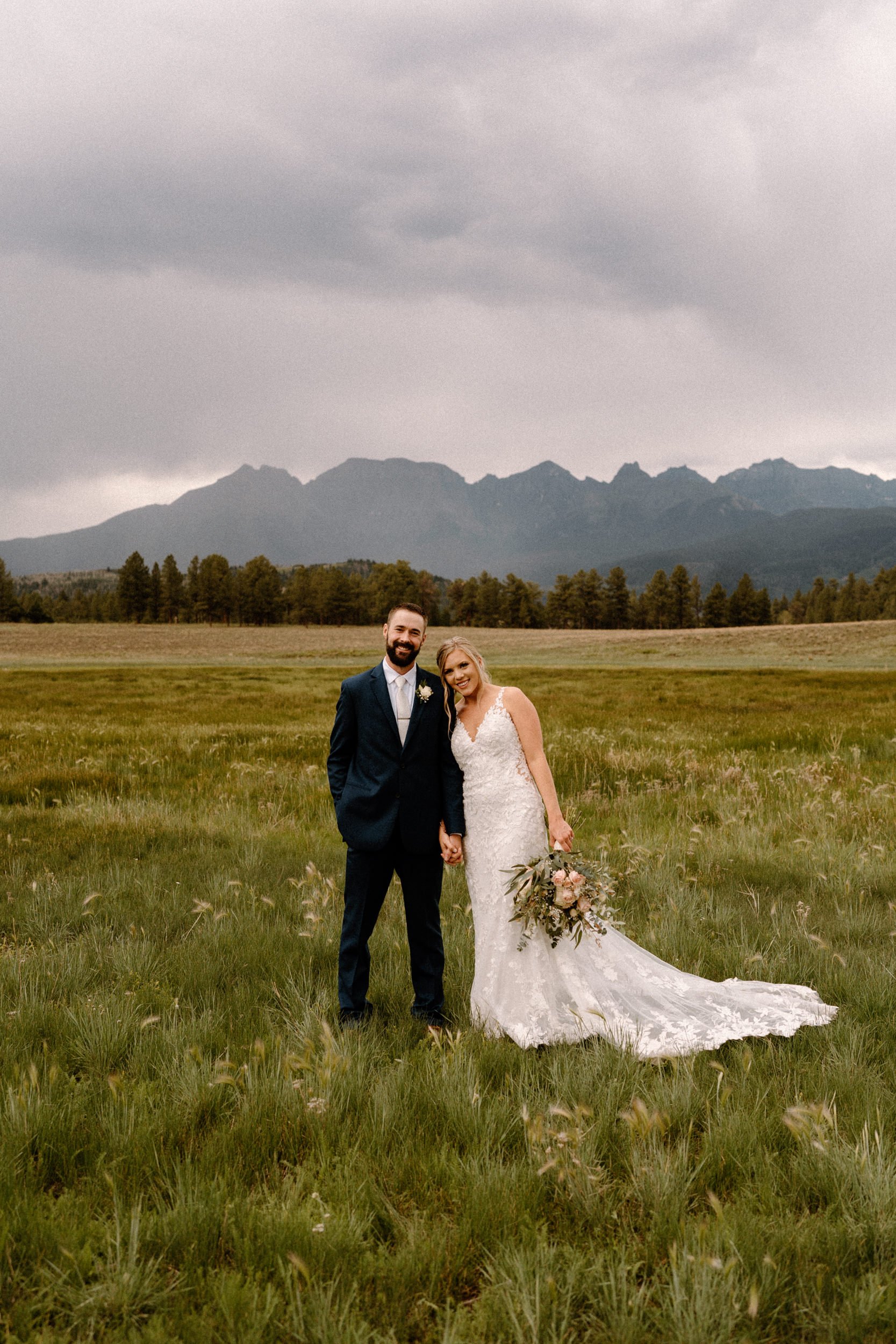 Bride and groom pose in front of mountains at Top of the Pines in Ridgway, CO