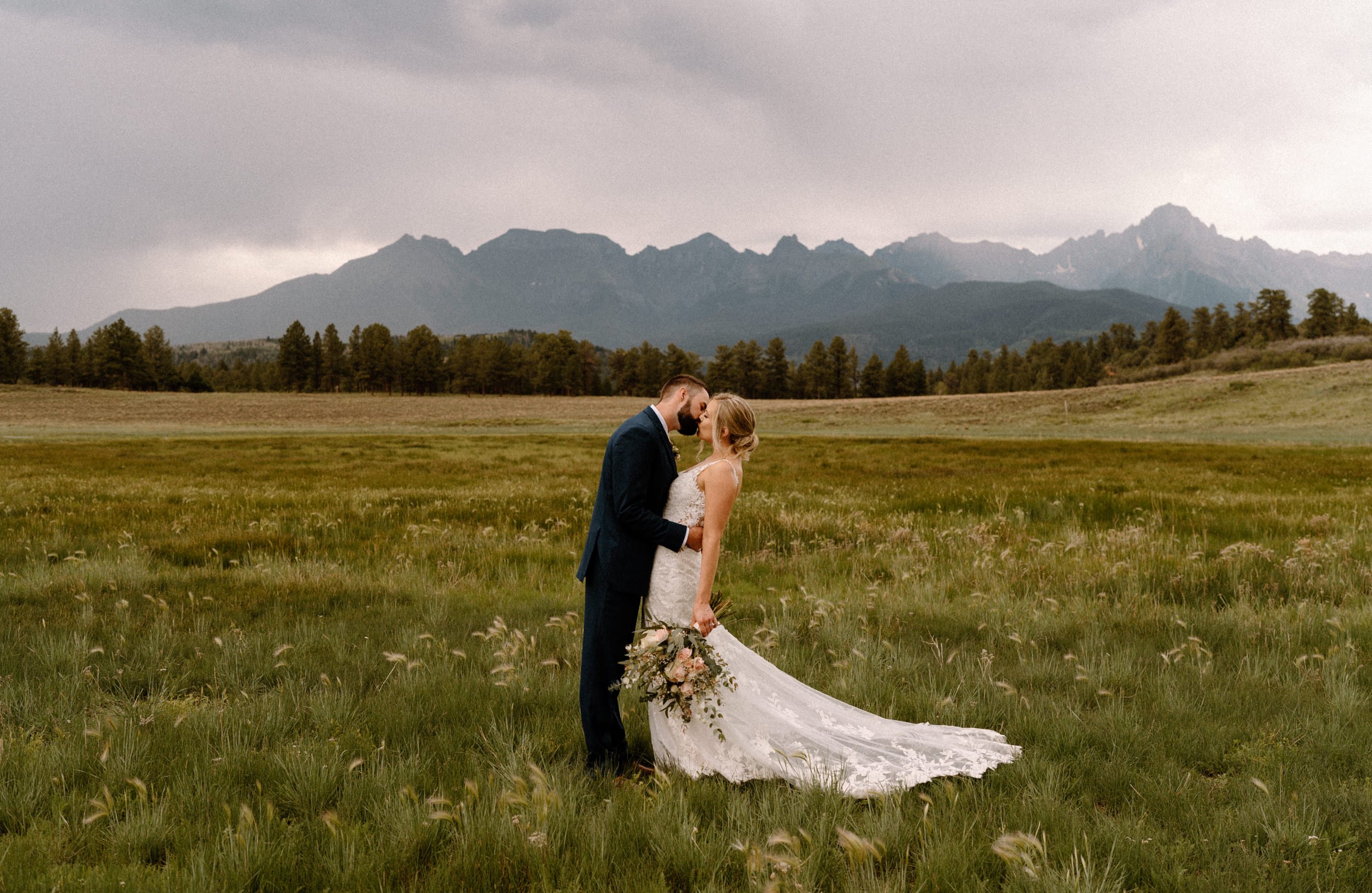 Bride and groom kiss in a valley at Top of the Pines in Ridgway, CO