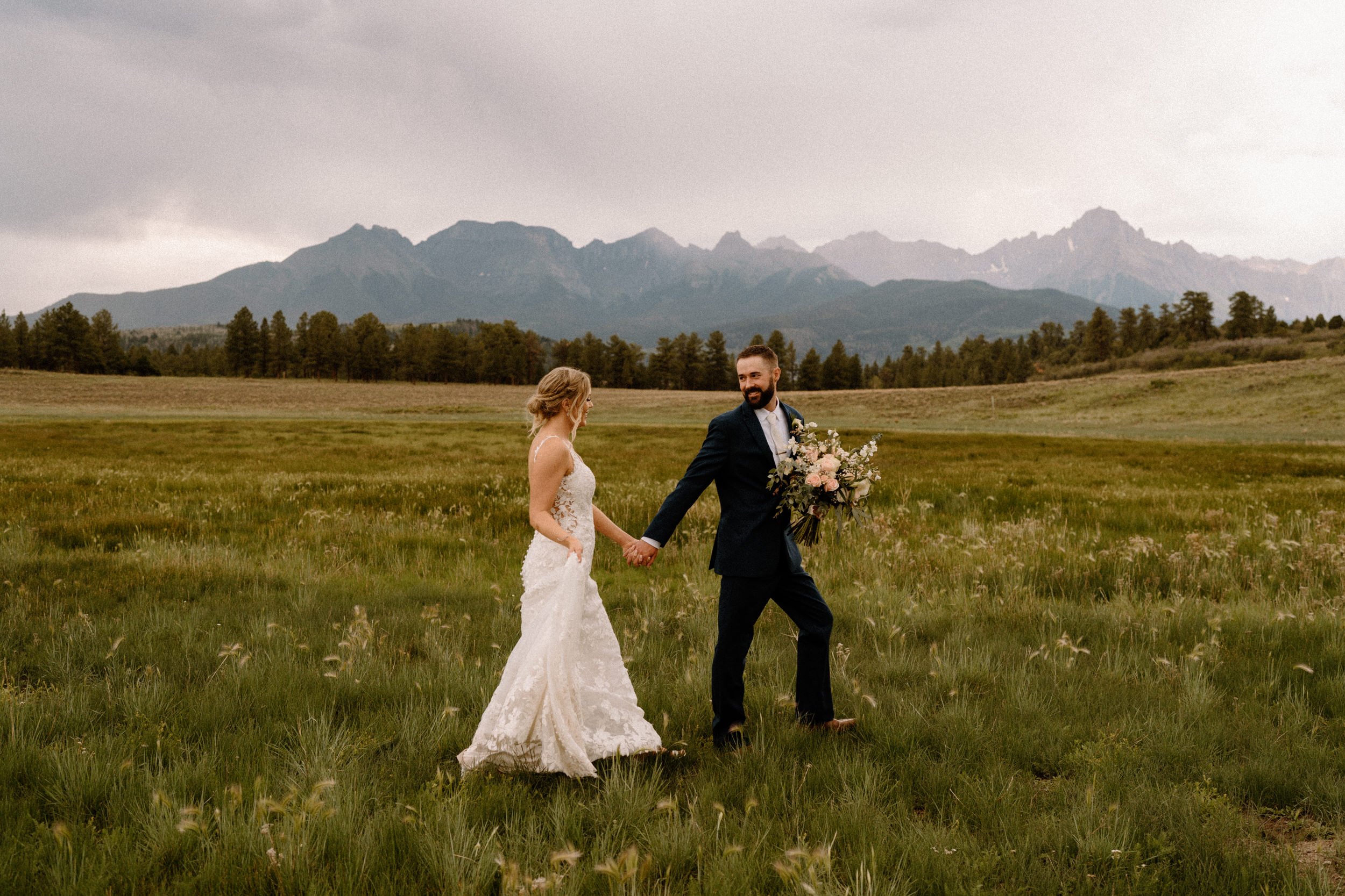 Groom leads bride in valley at Top of the Pines in Ridgway, CO