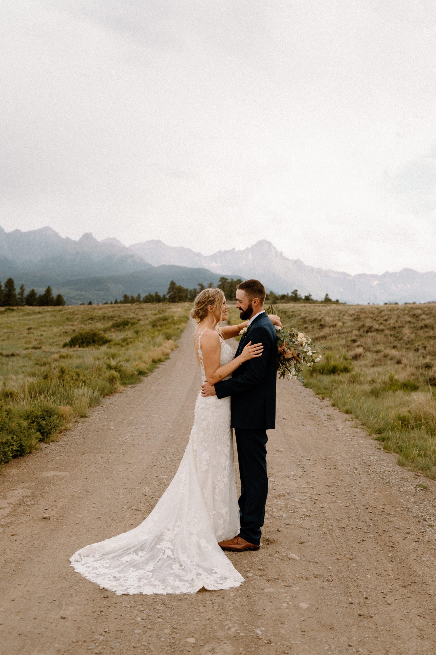 Bride and groom pose on dirt road at Top of the Pines in Ridgway, CO