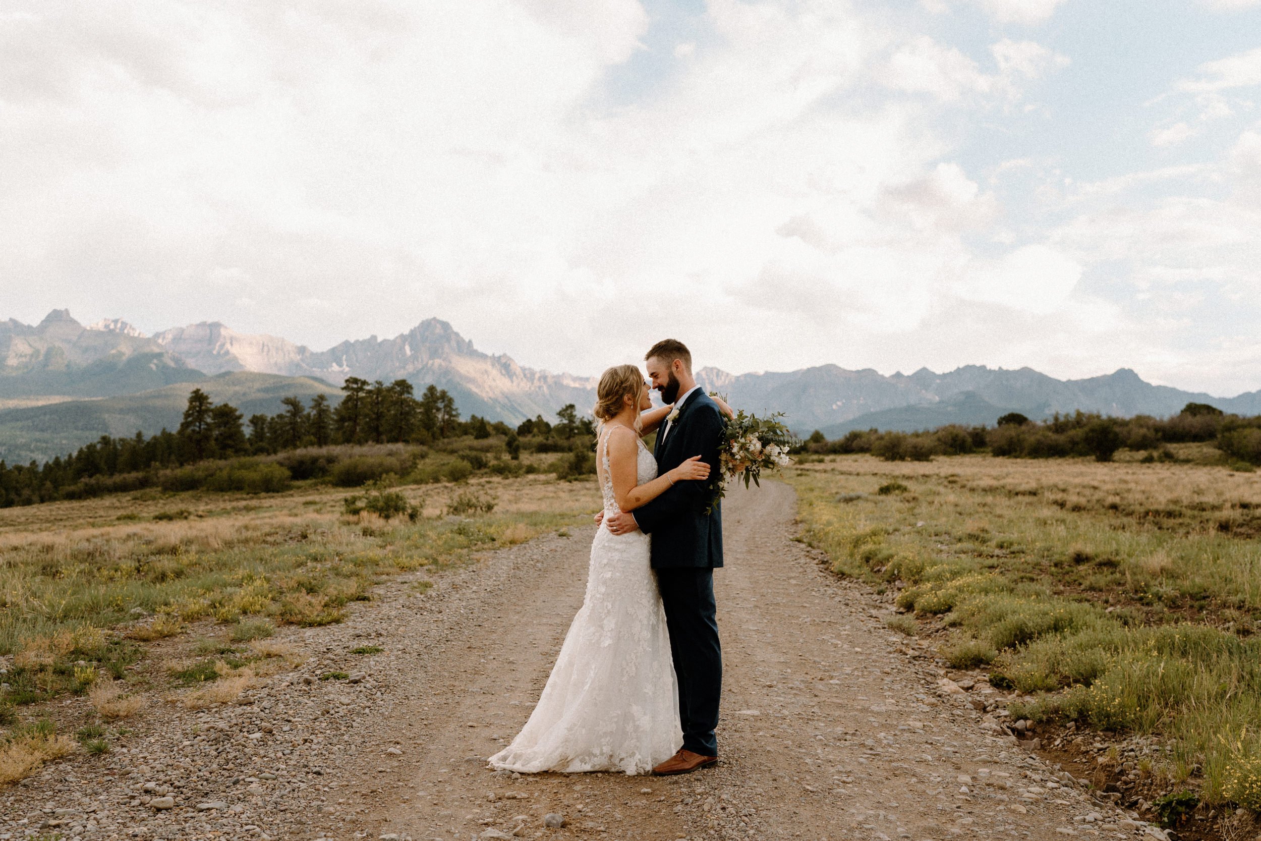 Bride and groom pose on dirt road at Top of the Pines in Ridgway, CO
